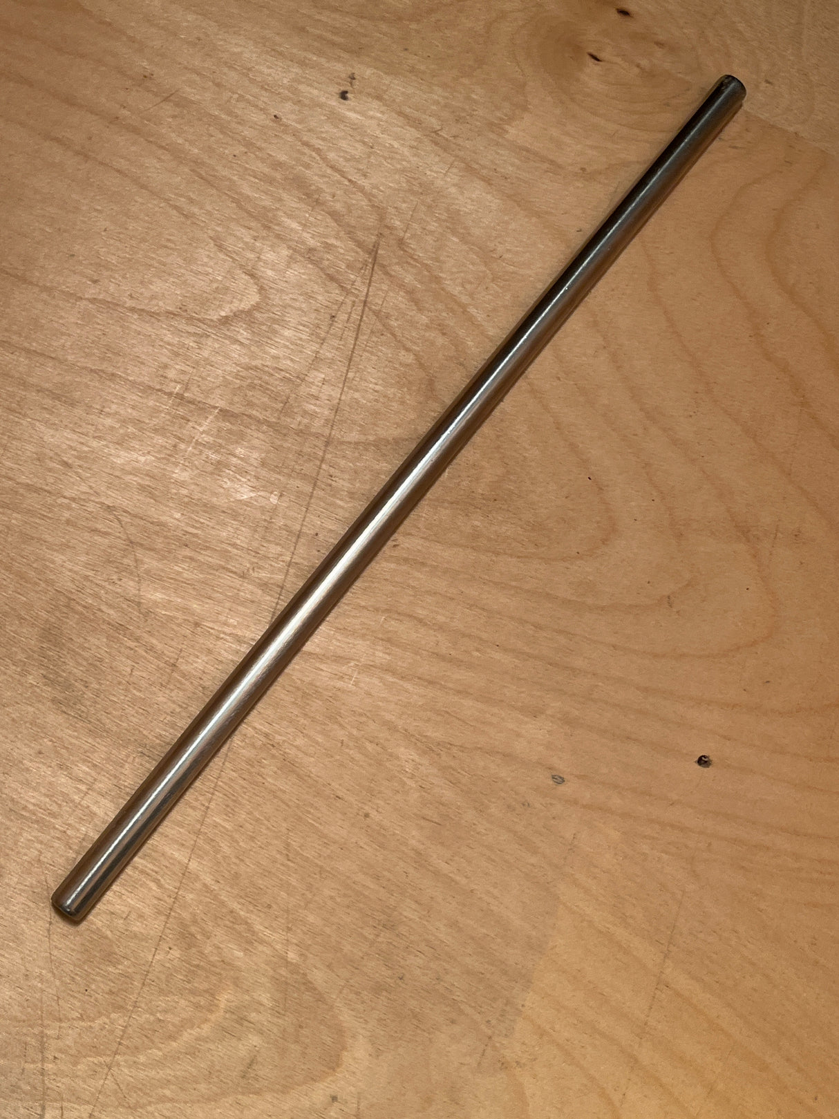 Stainless steel reusable drinking straw on a wooden surface, showcasing its sleek and durable design for eco-friendly beverage consumption.