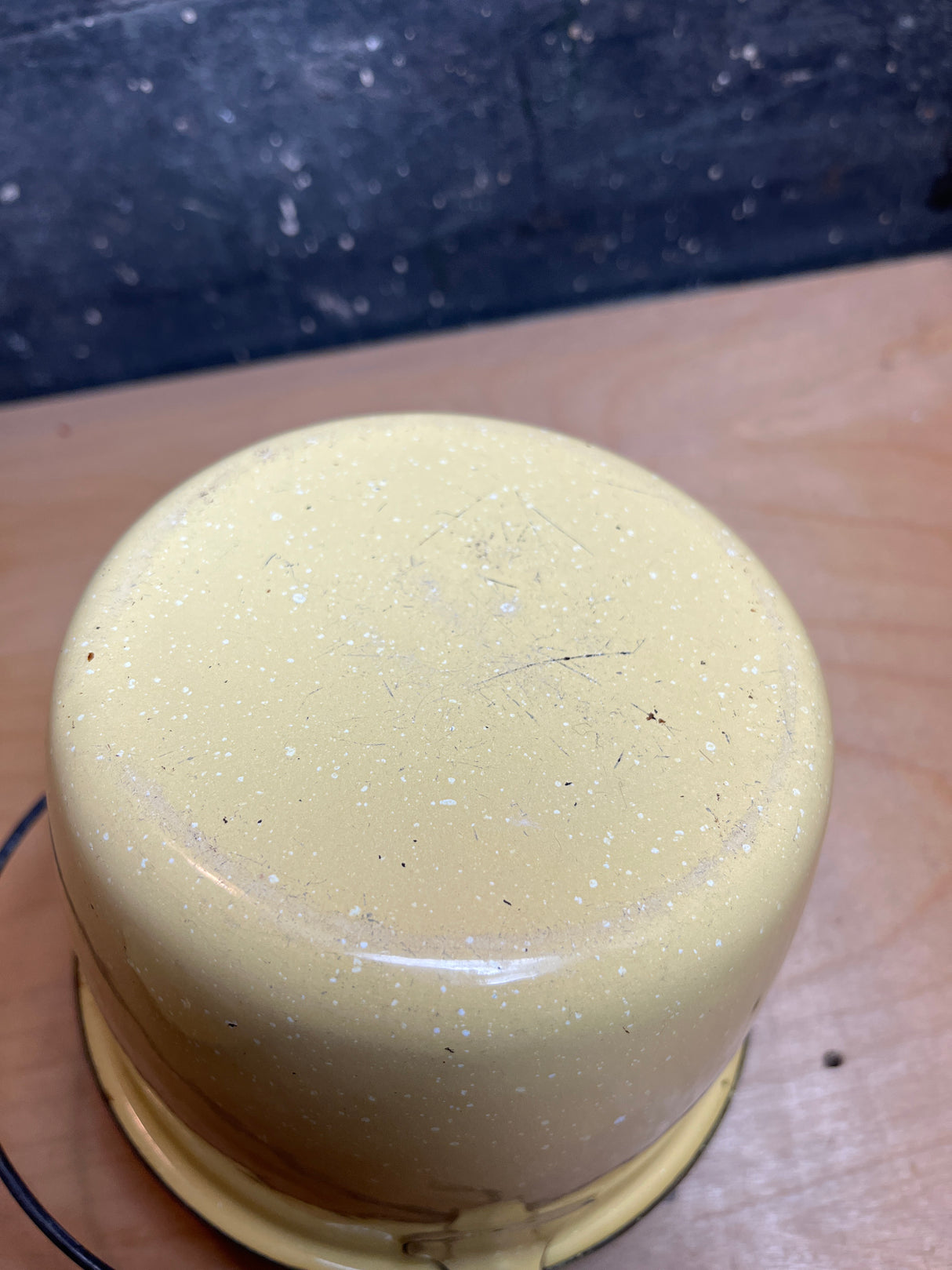 Mini pot with lid and wire handle - vintage enamelware in yellow with brown accents, showcasing its speckled underside on a wooden surface, ideal for garden adventures.