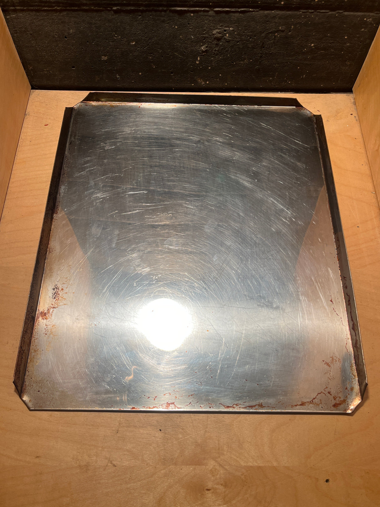 Stainless steel baking pan - vintage Sears with a shiny, slightly scratched surface, featuring low metal lips, resting in a wooden drawer.