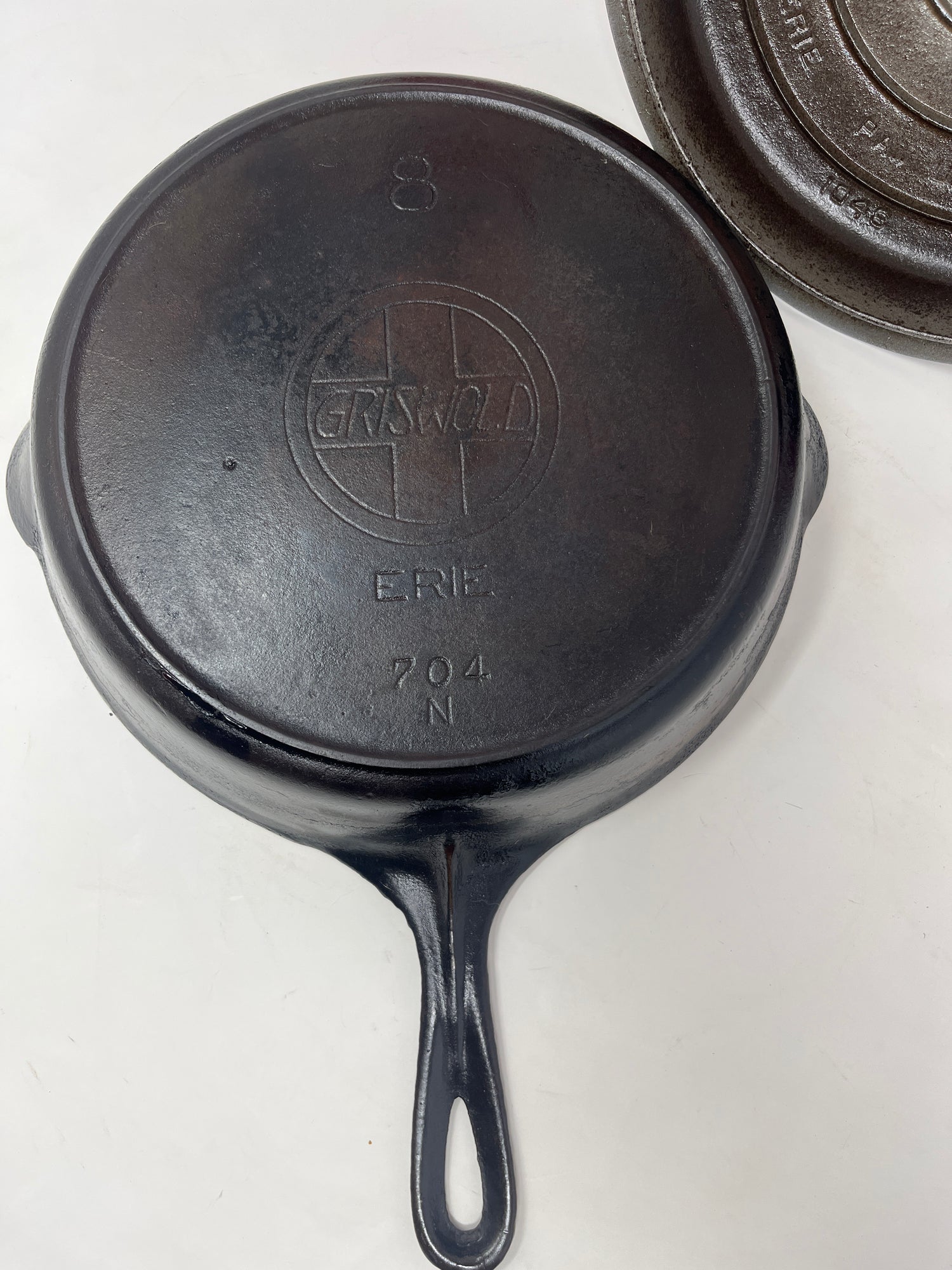 Vintage Griswold skillet and chrome lid from the 1930s, titled Untitled May22_10:36, with visible surface wear and uneven seasoning, in excellent working condition.