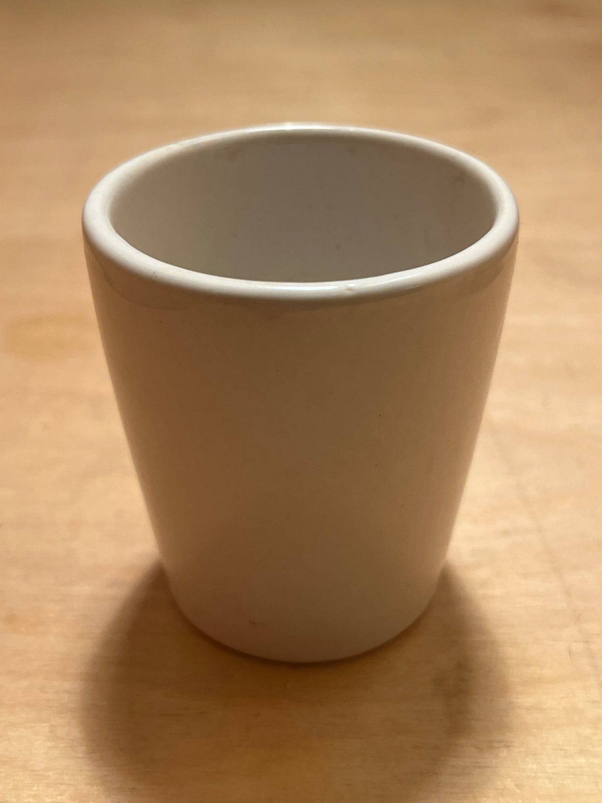 Teeny weeny espresso cup, a small white ceramic tumbler with smooth sides and a rounded rim, ideal for a single espresso shot.