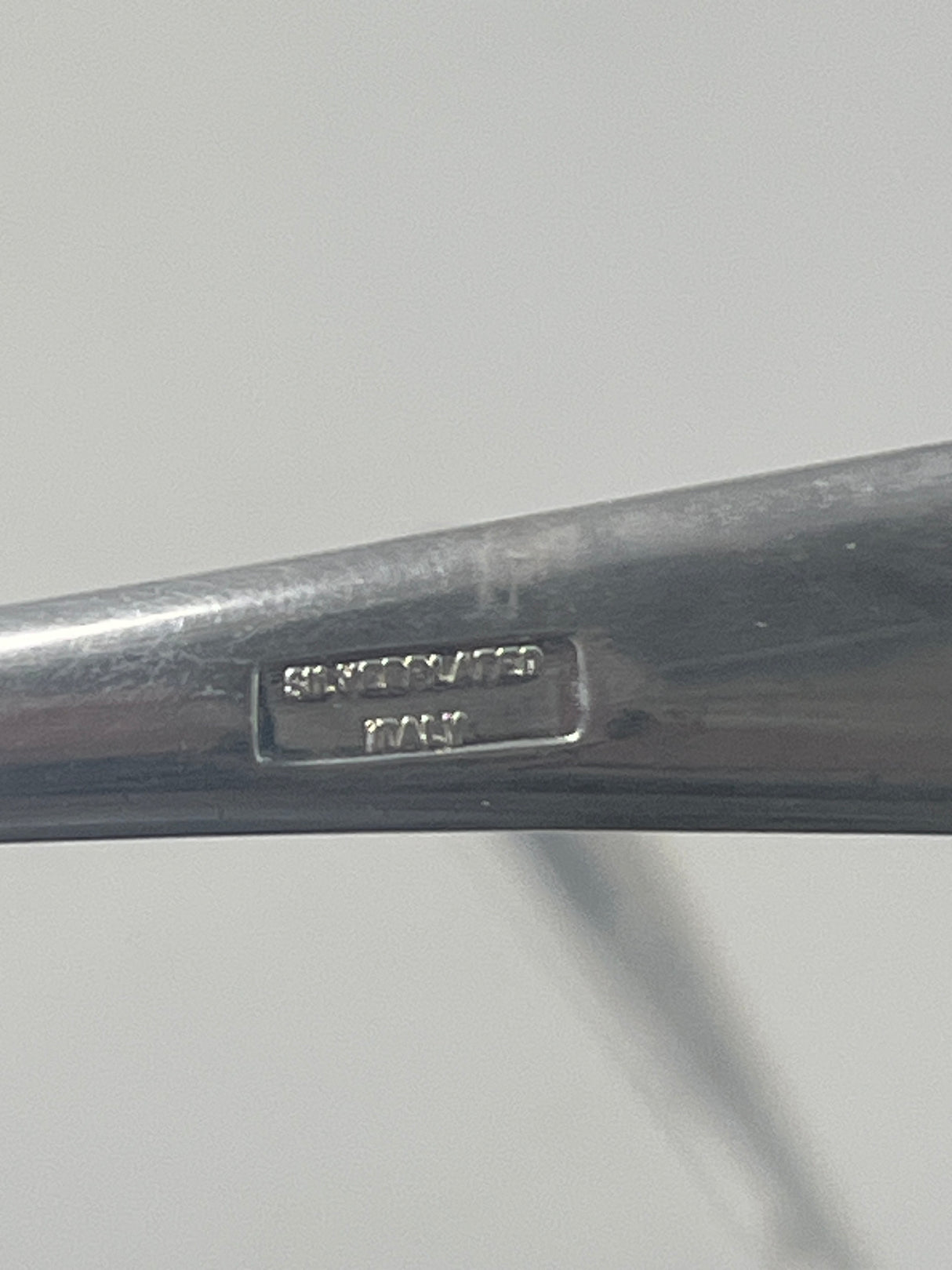 Italian silver plated salad tongs with a minimalist design, showing a close-up of their handle with visible tarnish from use, reflecting their 1970s origin.