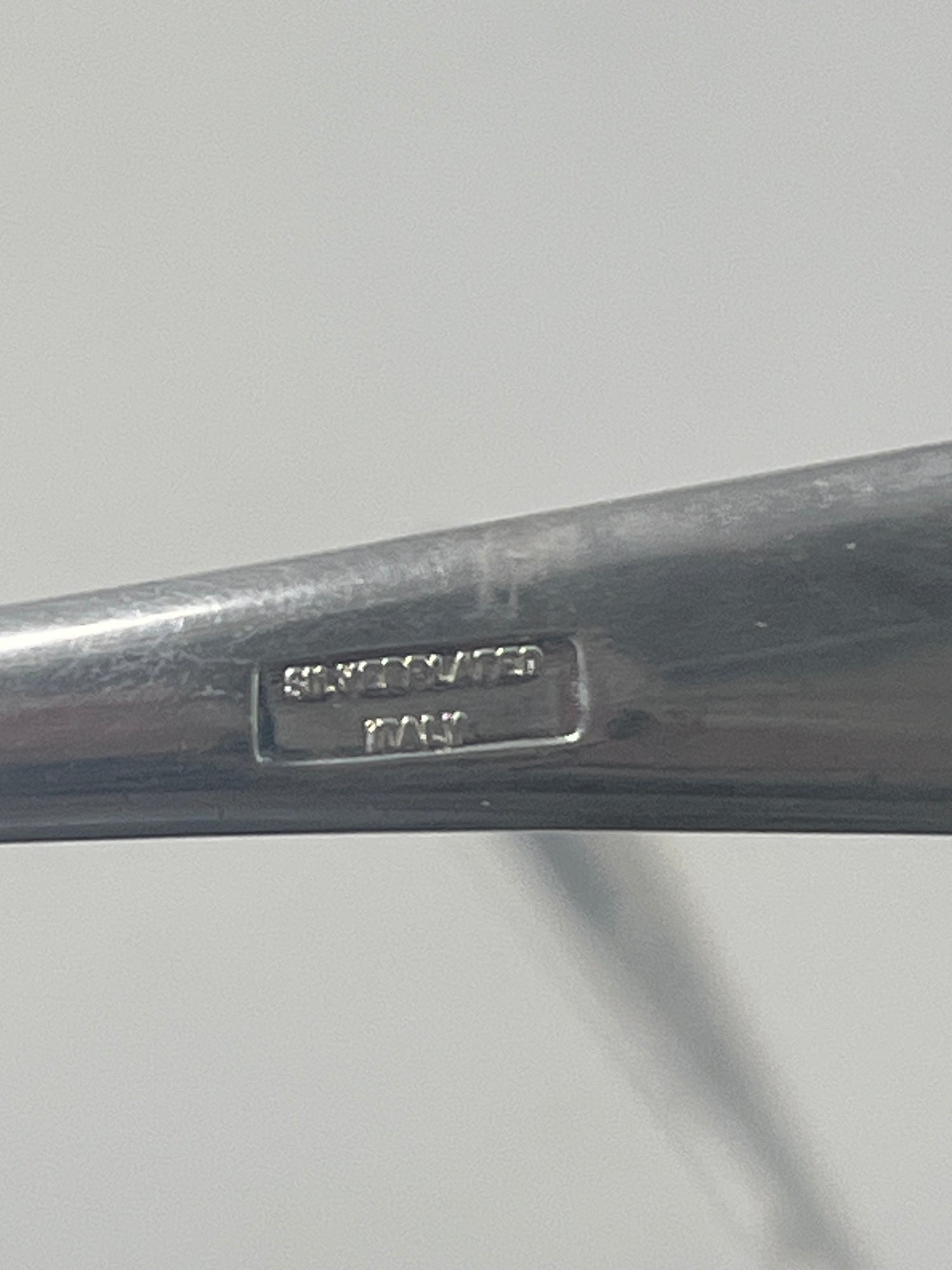 Italian silver plated salad tongs with a minimalist design, showing a close-up of their handle with visible tarnish from use, reflecting their 1970s origin.