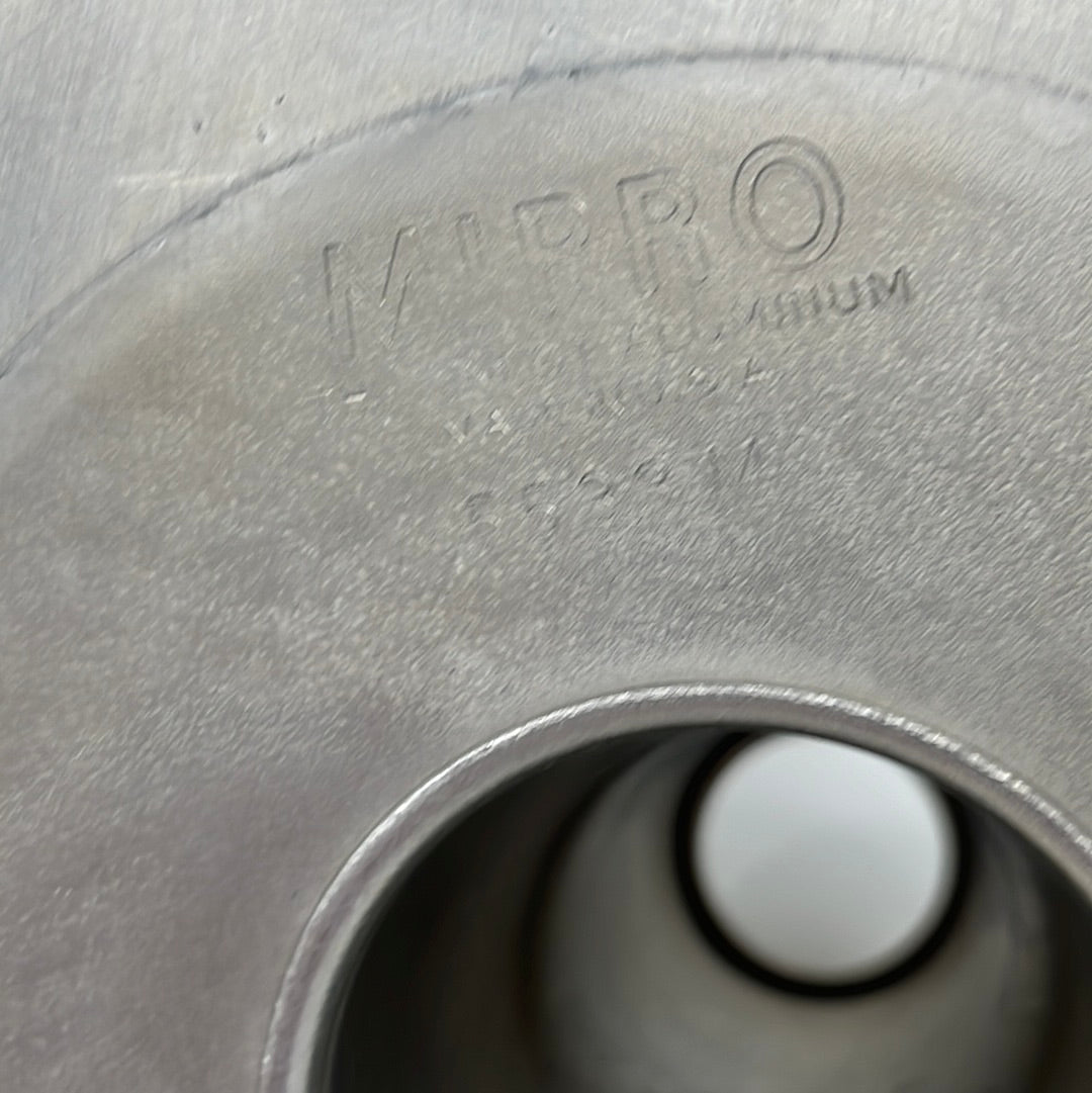 The image shows a close-up of a surface with embossed lettering, possibly a part of a Mirro kitchen spoon, with a circular hole visible towards the bottom right.