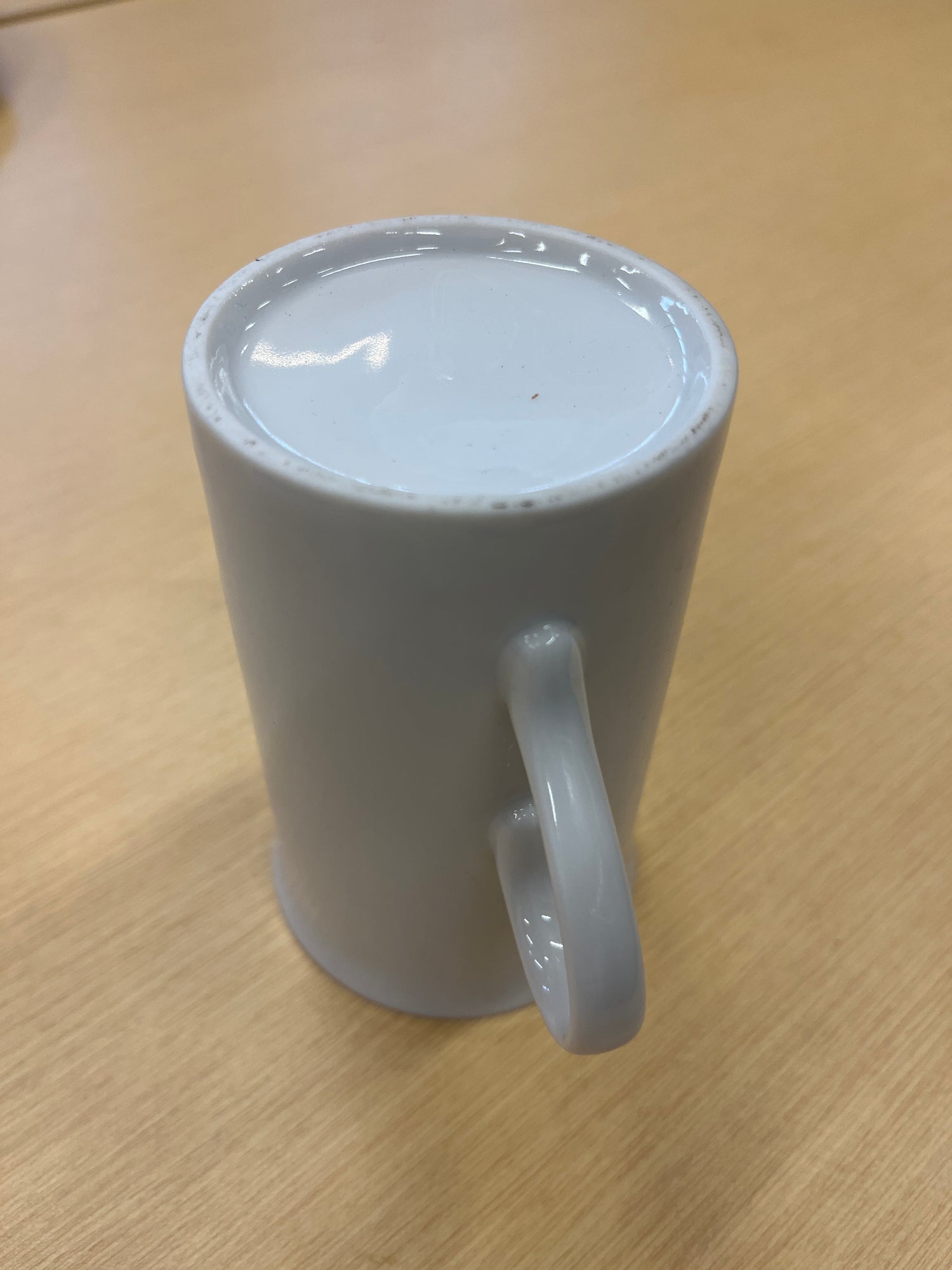 Tall ceramic white coffee mug with a smooth finish and a delicate, offset handle, ideal for everyday use. Elegant and timeless design.