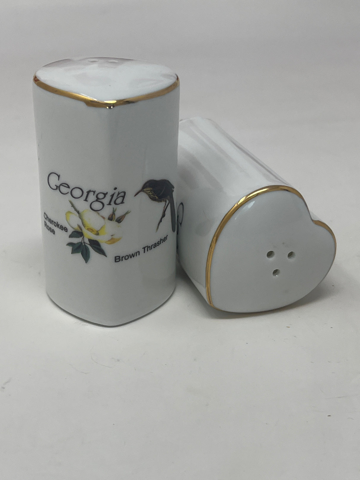 Ceramic heart-shaped salt and pepper shaker set with Georgia's Brown Thrasher and Cherokee Rose design, highlighting its intricate detailing and unique shape.