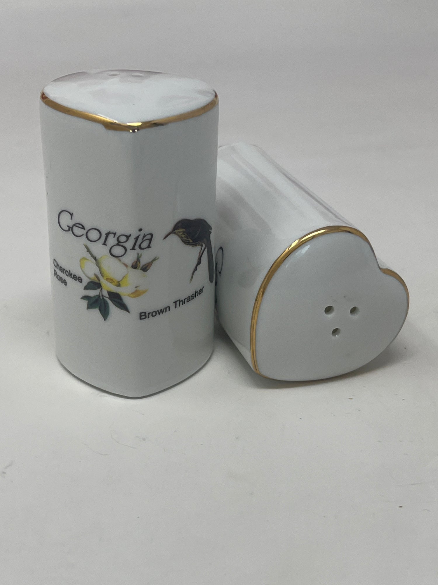 Ceramic heart-shaped salt and pepper shaker set with Georgia's Brown Thrasher and Cherokee Rose design, highlighting its intricate detailing and unique shape.