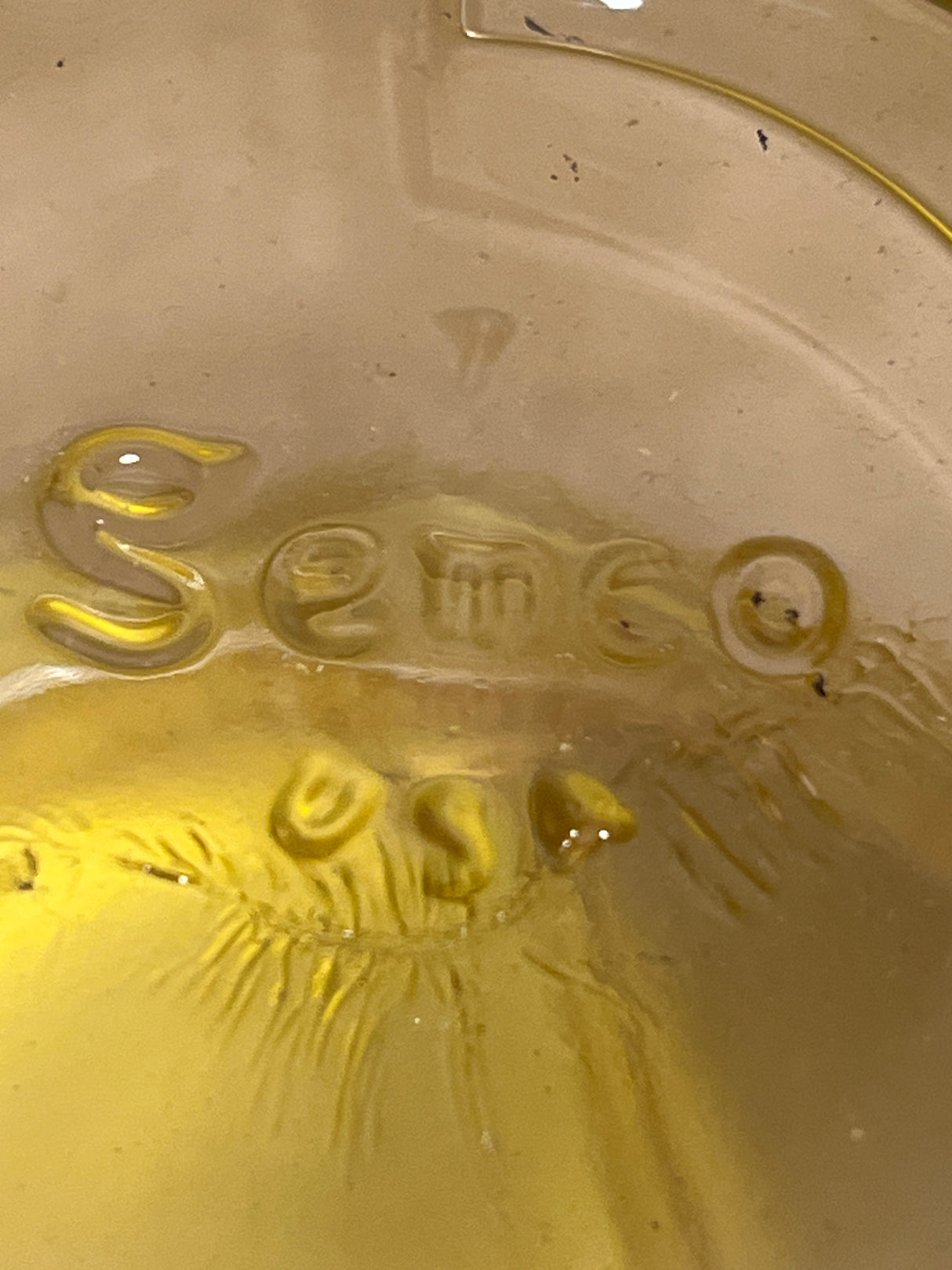 Underside of Gemco sugar and cream dispenser set, featuring an amber-tinted glass base with SEMCO USA embossed, showing a yellowish hue.