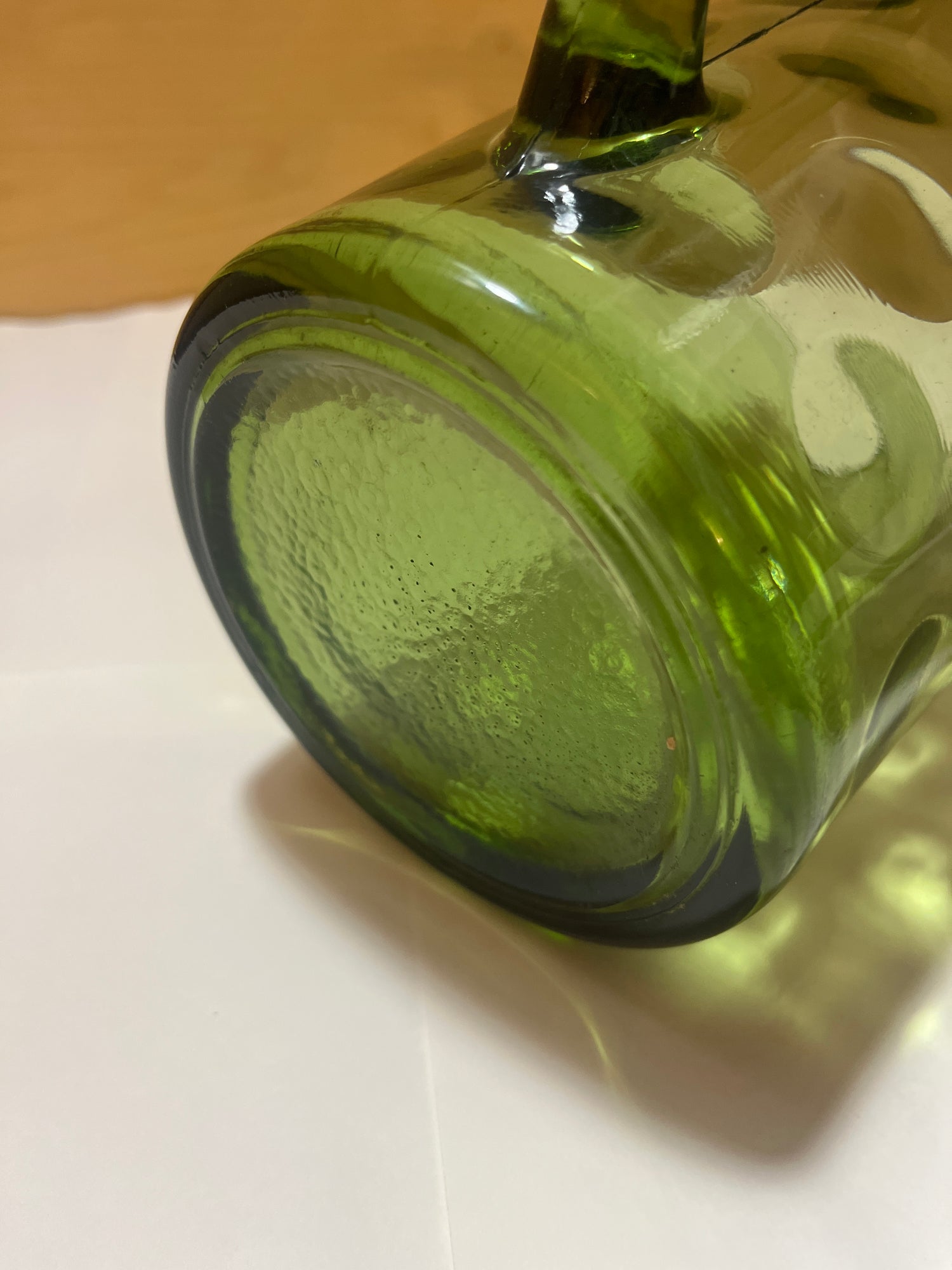 Hazel Atlas Eldorado avocado green coin dot glass pitcher shown on its side, highlighting the textured bottom and concentric rings of its midcentury modern design.