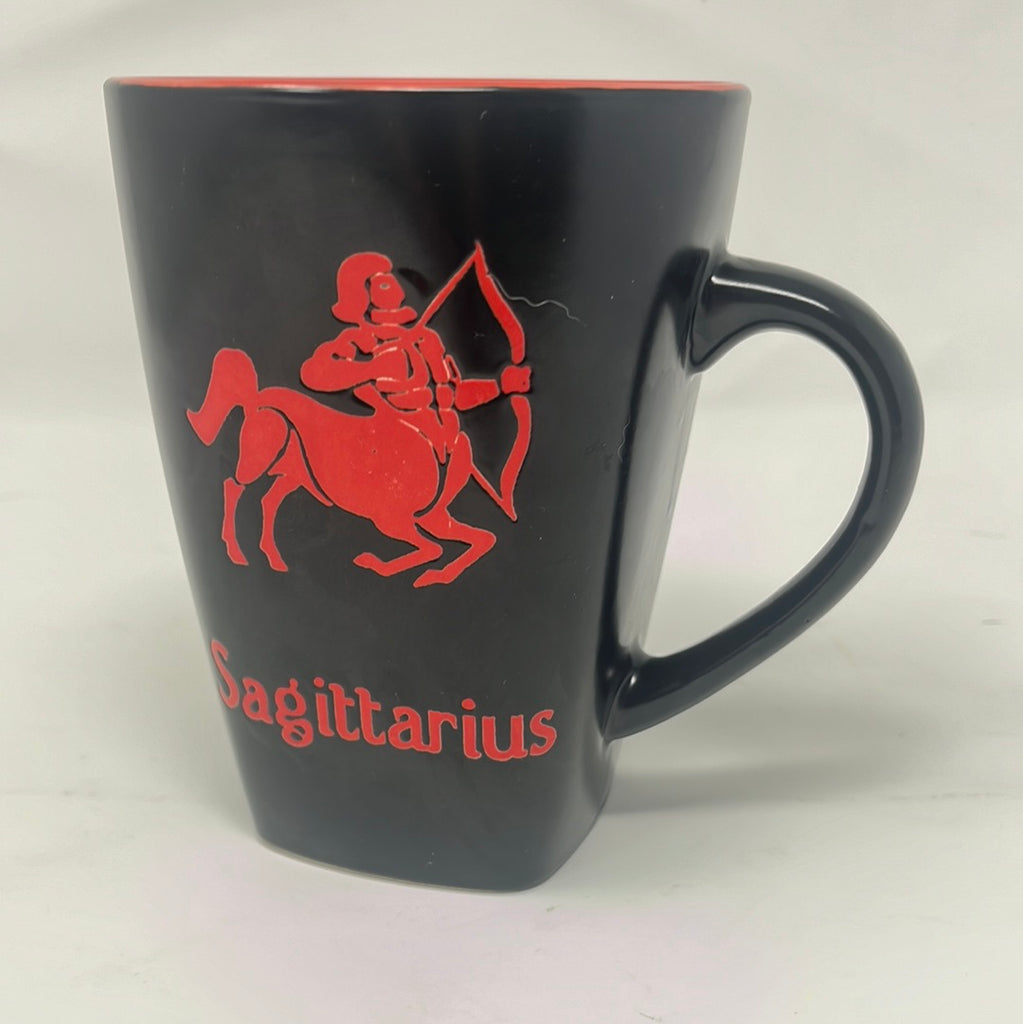 A black mug featuring Sagittarius text on the front and detailed zodiac traits on the back. Close-ups of the mug's handle and logo.