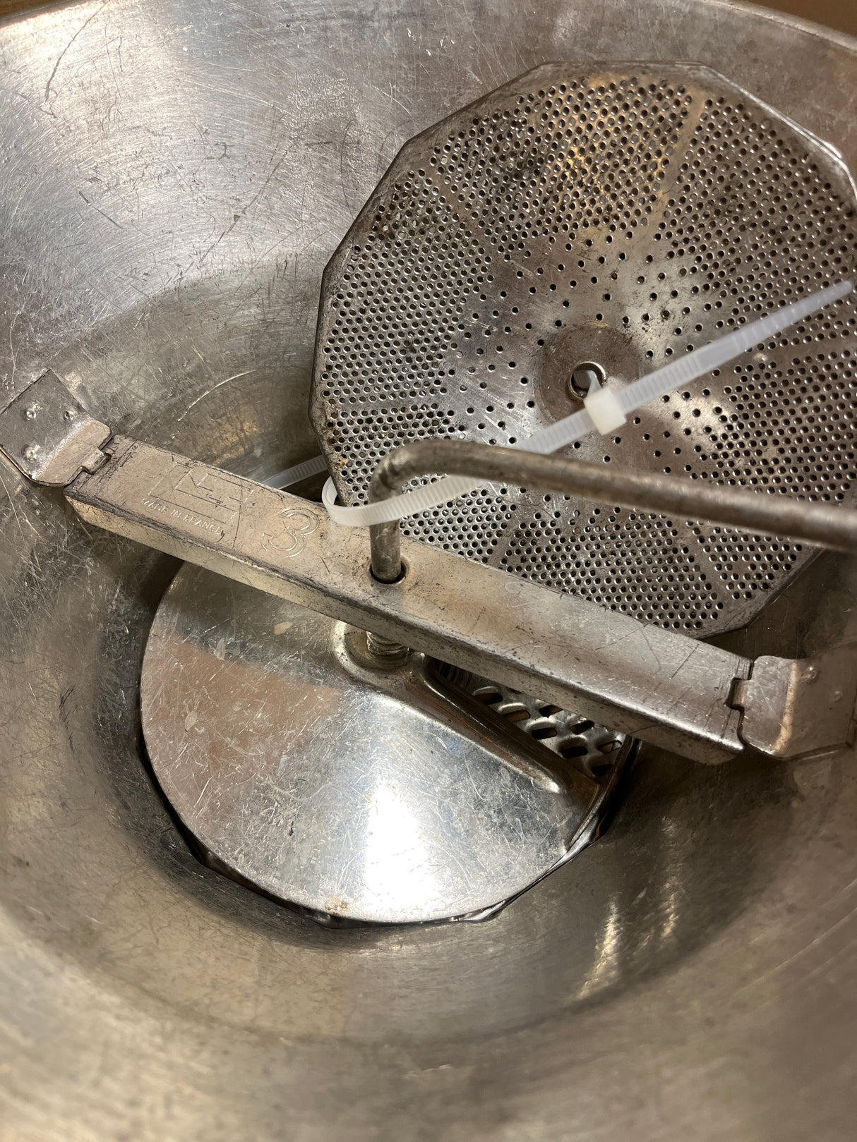 Louis Teller 3.5qt rotary food mill with hand-crank assembly, featuring a stainless-steel bowl and interchangeable milling plates, stabilized with a plastic zip-tie.