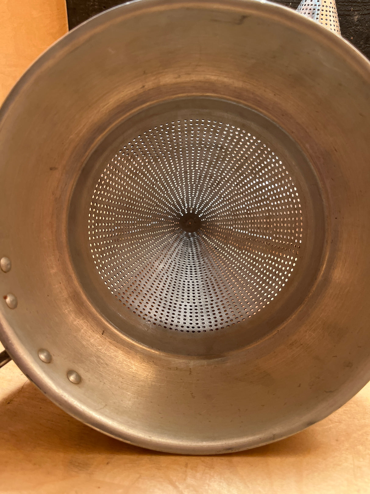 Tiny pointy cone sieve strainer - aluminum, shows perforated design for effective draining, sturdy handle, and a small dent at the cone tip. Ideal for canning tasks.