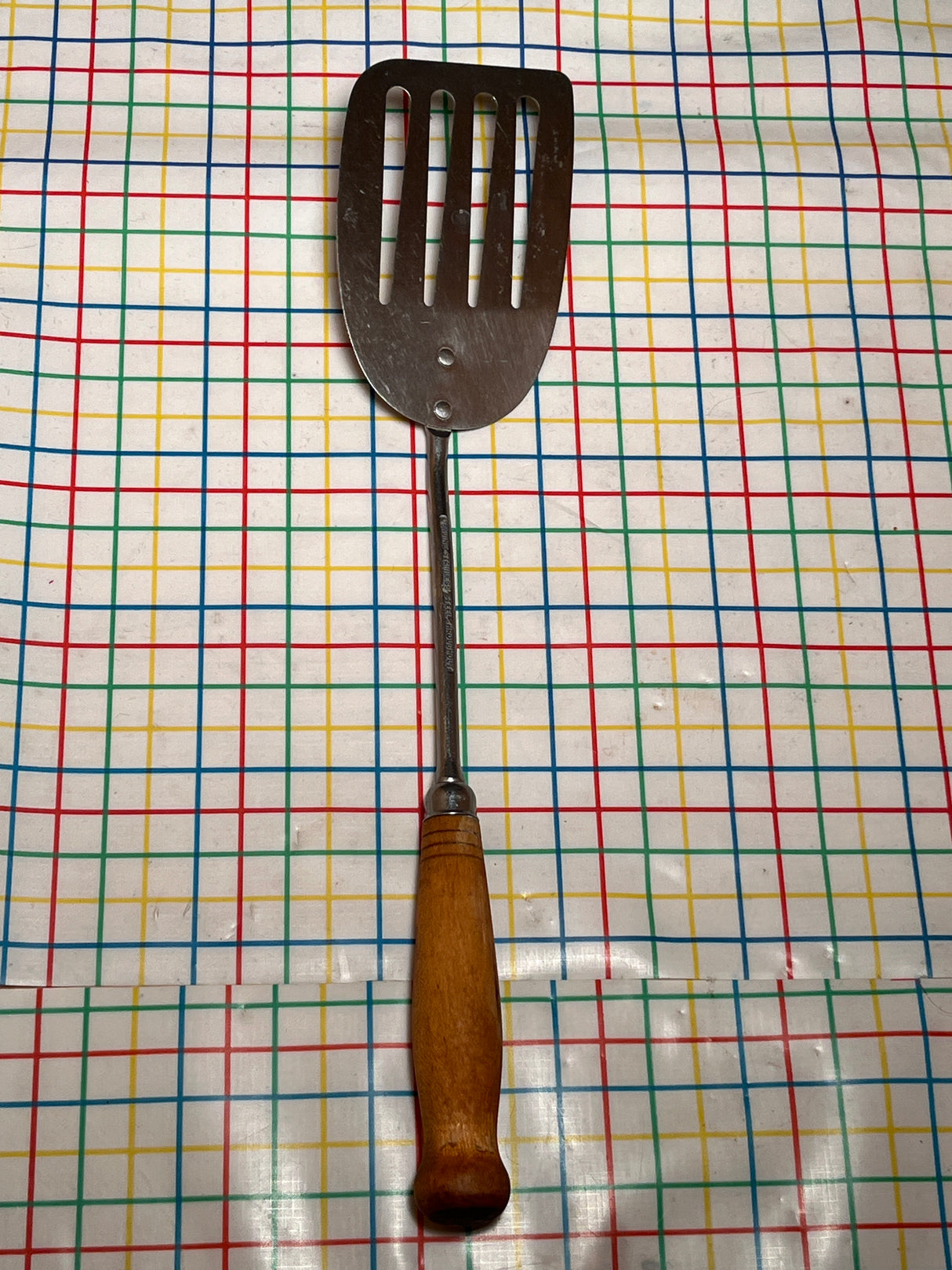 Flat thin steel slotted spatula with wood handle - vintage, shown lying flat, features a long handle, thin edge, and slots for easy flipping and grilling.