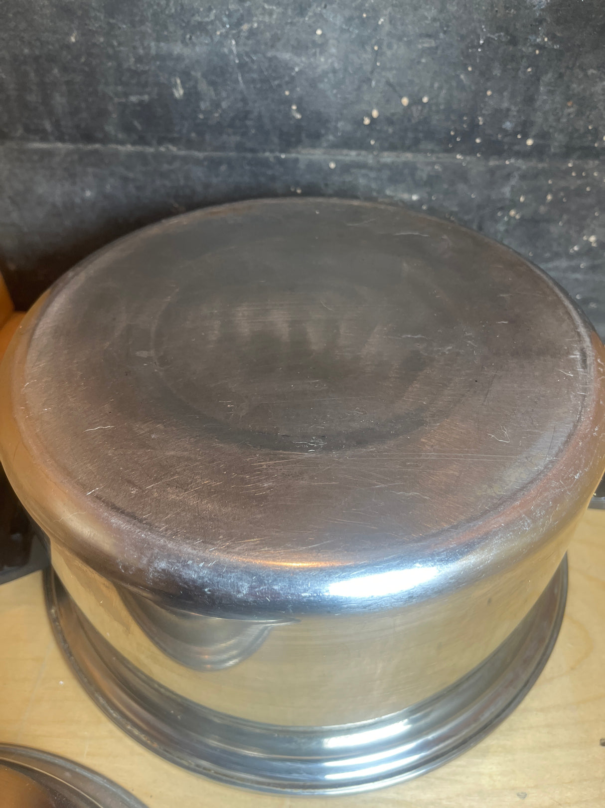 Upside-down vintage Duncan Hines stock pot, 3-ply 18-8 stainless steel. Features black handles and lid, showcasing its durable construction.