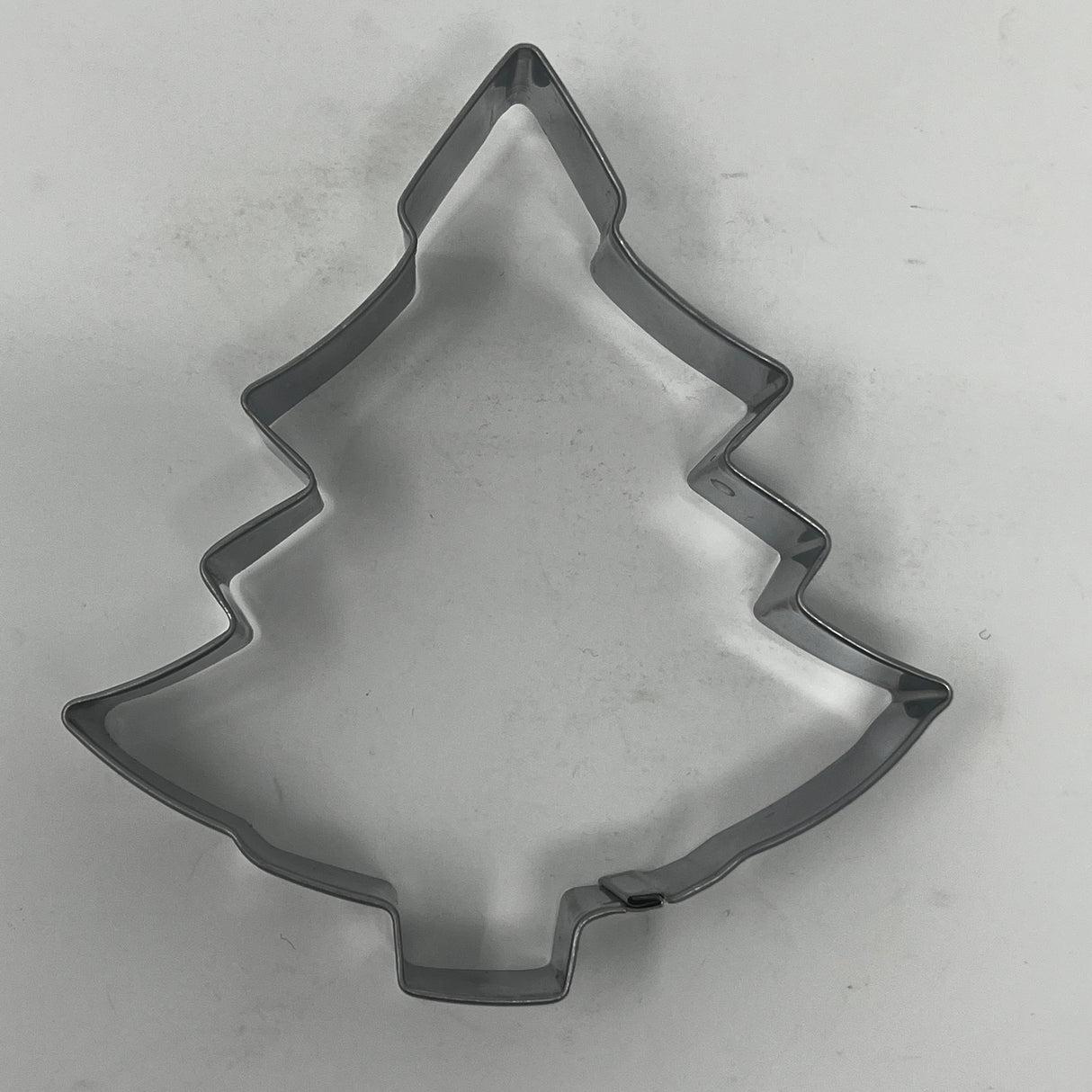 Mid-century metal cookie cutter in a tree shape, part of an adaptive collection featuring easy-grip handles, ideal for creating festive or celestial-themed cookies.