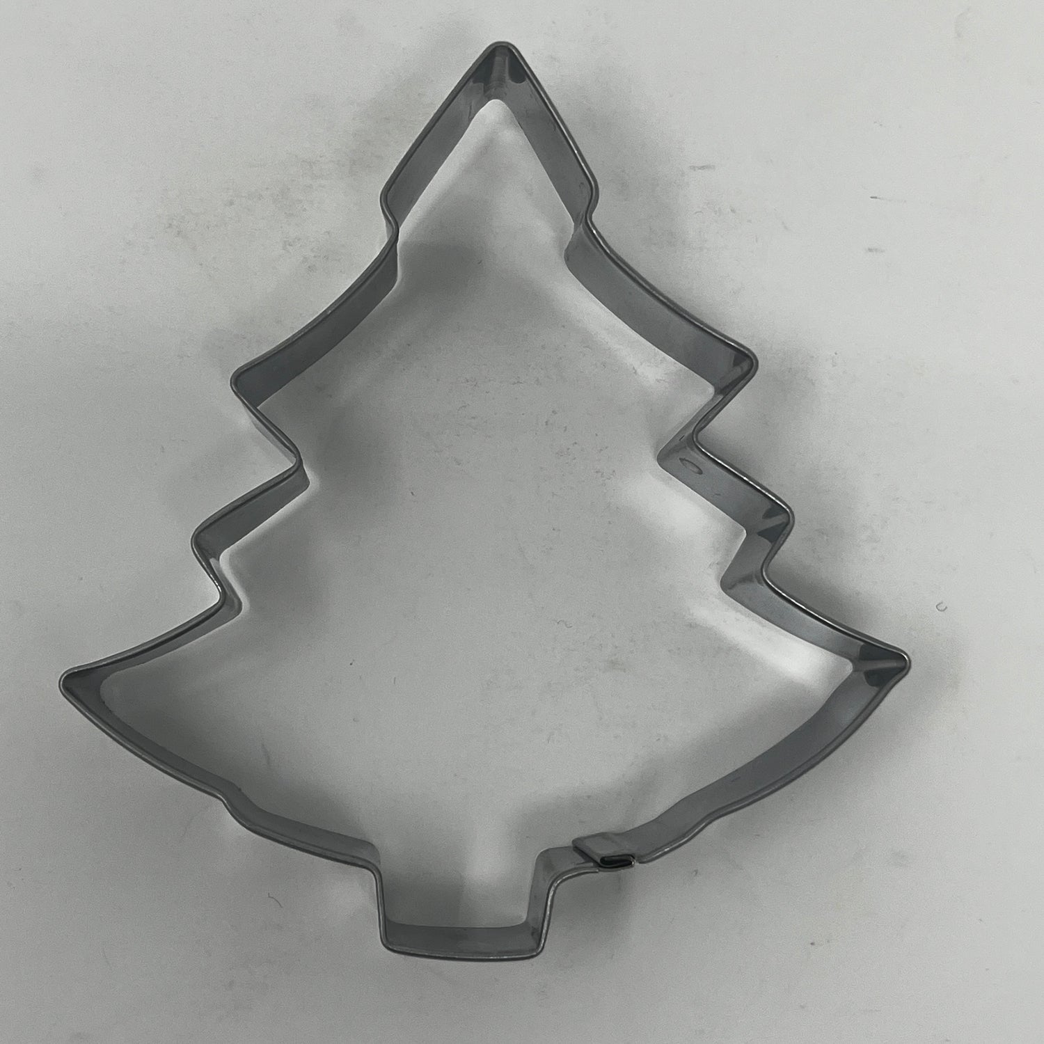 Mid-century metal cookie cutter in a tree shape, part of an adaptive collection featuring easy-grip handles, ideal for creating festive or celestial-themed cookies.