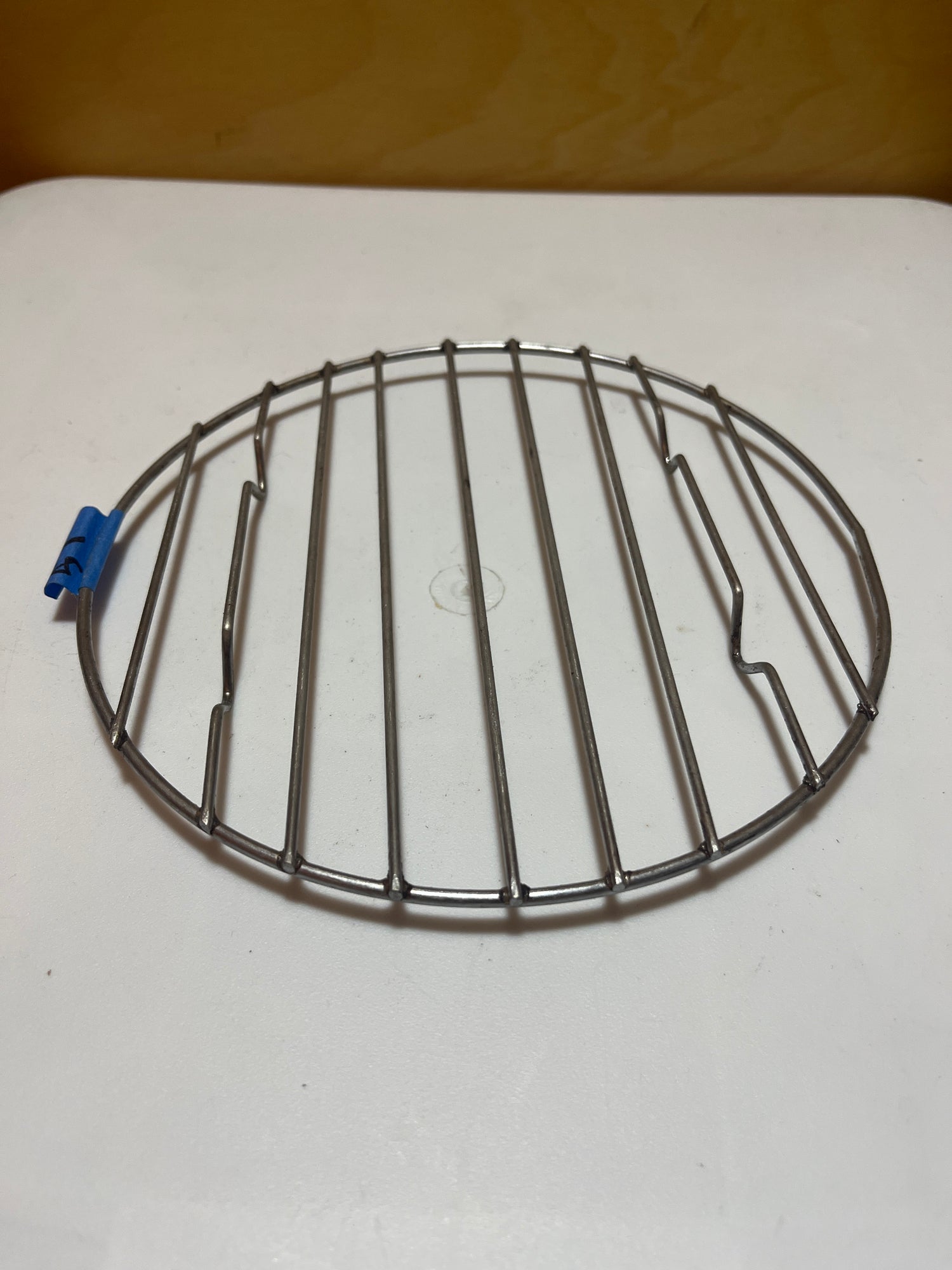 Small circular wire cooling rack with raised feet, versatile for use as a tray or cooling rack for pots and pans.