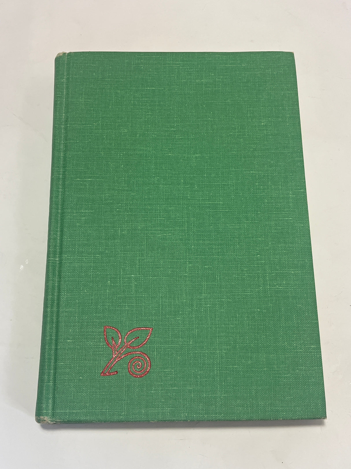 Leone’s Italian Cookbook (1967 First Edition) with a plain green cover, featuring a red leaf graphic in the corner, photographed on a white surface.