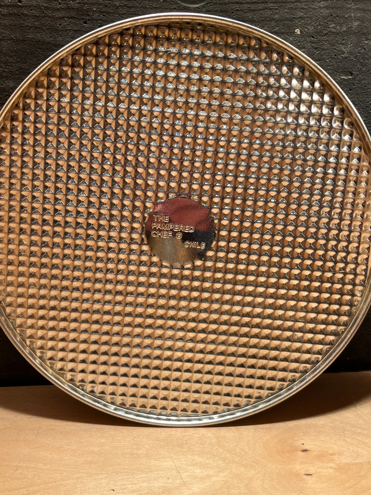 4-piece springform pan set - Pampered Chef includes a round, perforated pizza pan with a center medallion stamped “THE PAMPERED CHEF ® • CHILE.”