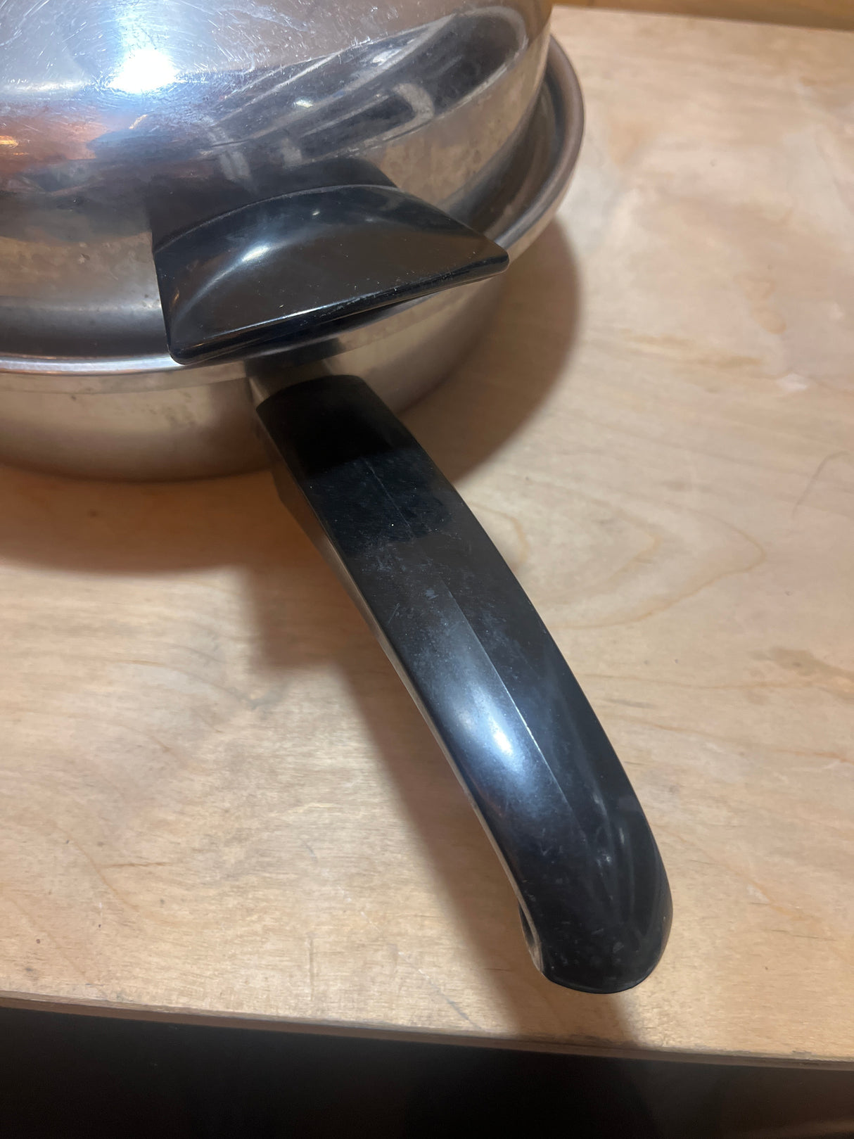 Seal-O-Matic Thermium Multi-Plex 18-8 Stainless Steel 11” Skillet with Lid features black handles, flat base, and secure lid for even heating on a wood countertop.