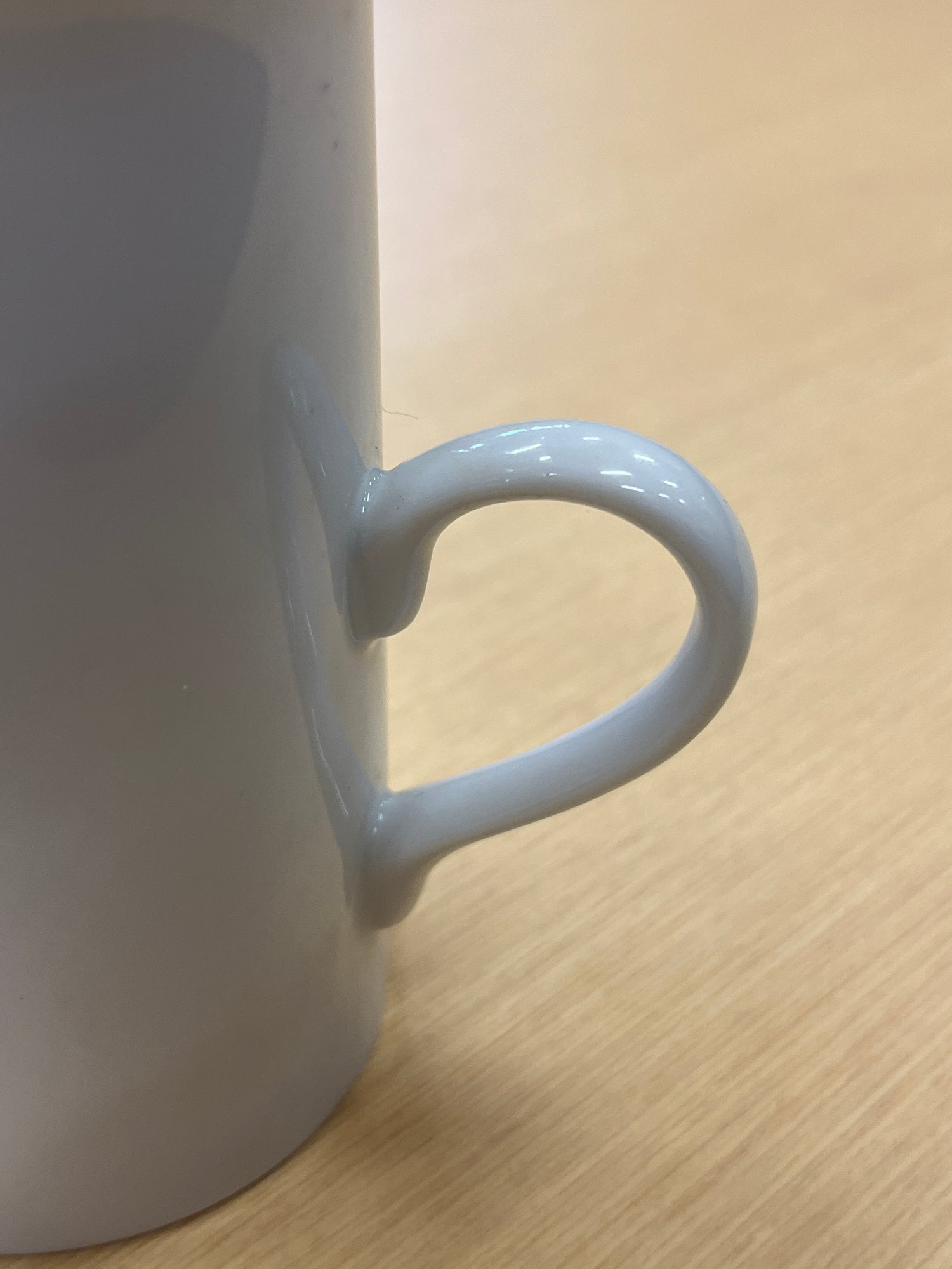 Close-up of tall ceramic white coffee mug with delicate, modern handle, showcasing its elegant design and smooth glaze. Part of an everyday coffee mug set.