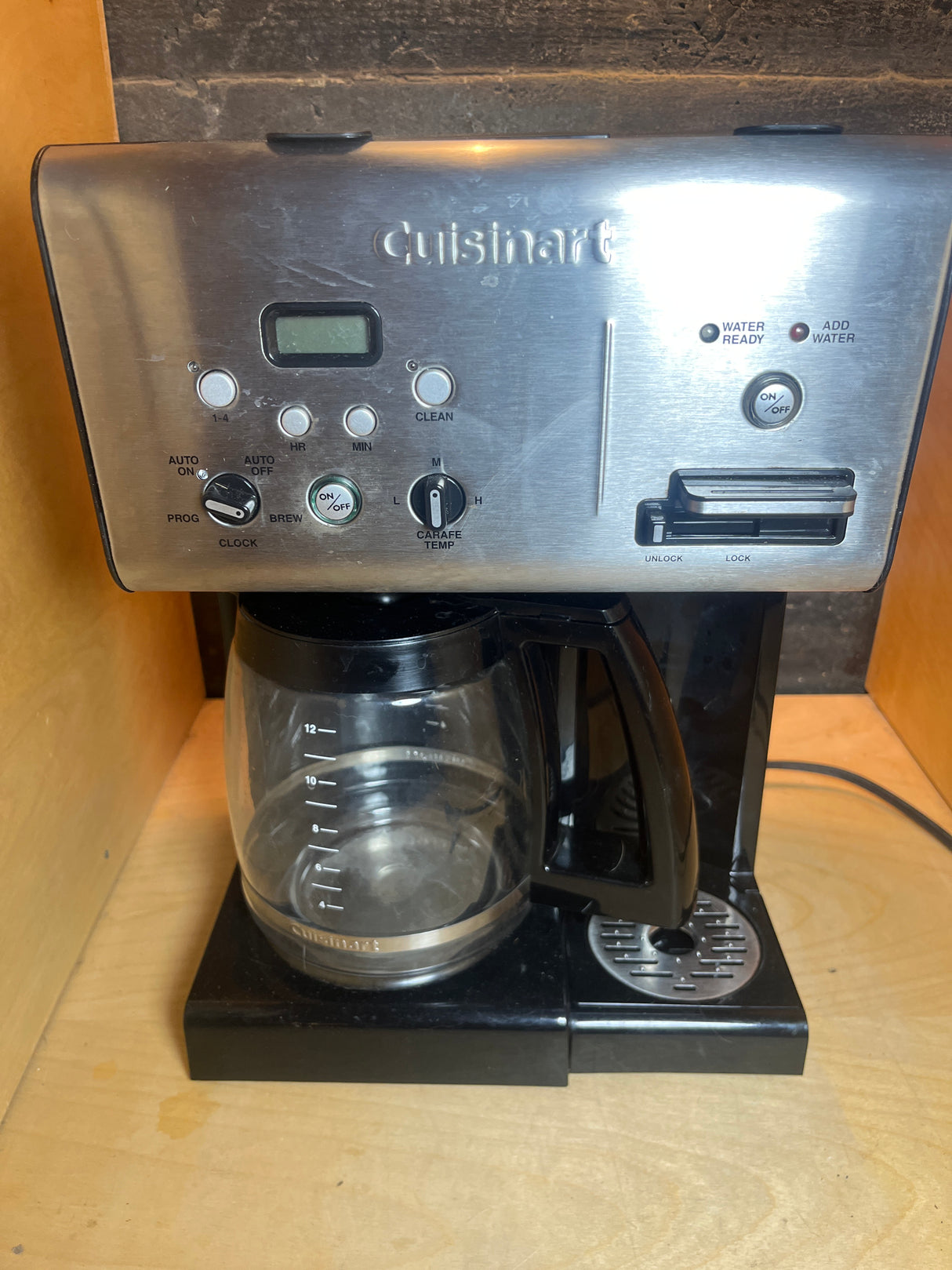 12-cup Cuisinart coffee maker with hot water dispenser, featuring a digital clock, programmable buttons, carafe temperature dial, and a 12-cup glass carafe on a warming plate.
