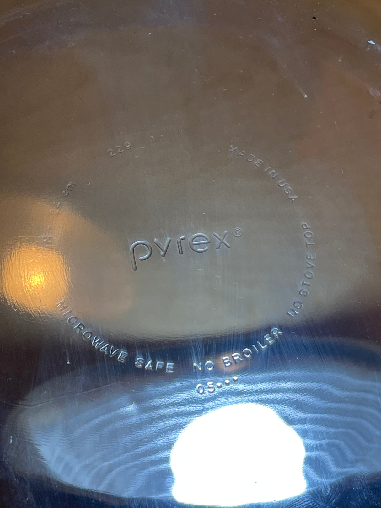 Underside of a Pyrex 229 cobalt blue glass pie/casserole dish with fluted edges, showing embossed brand markings and safety instructions.