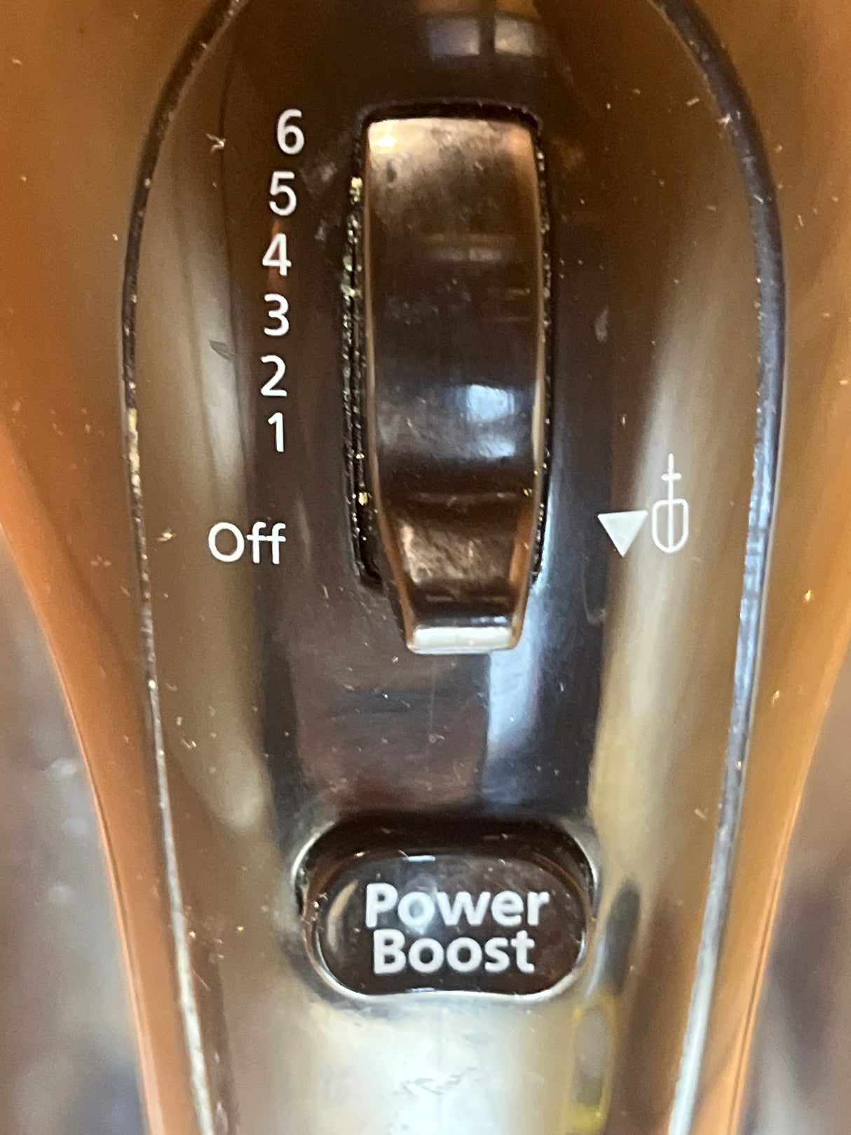 Close-up of the Oster 6-speed 2577 hand mixer control pod, showing speed settings dial, pulse icon, and Power Boost button for versatile mixing.