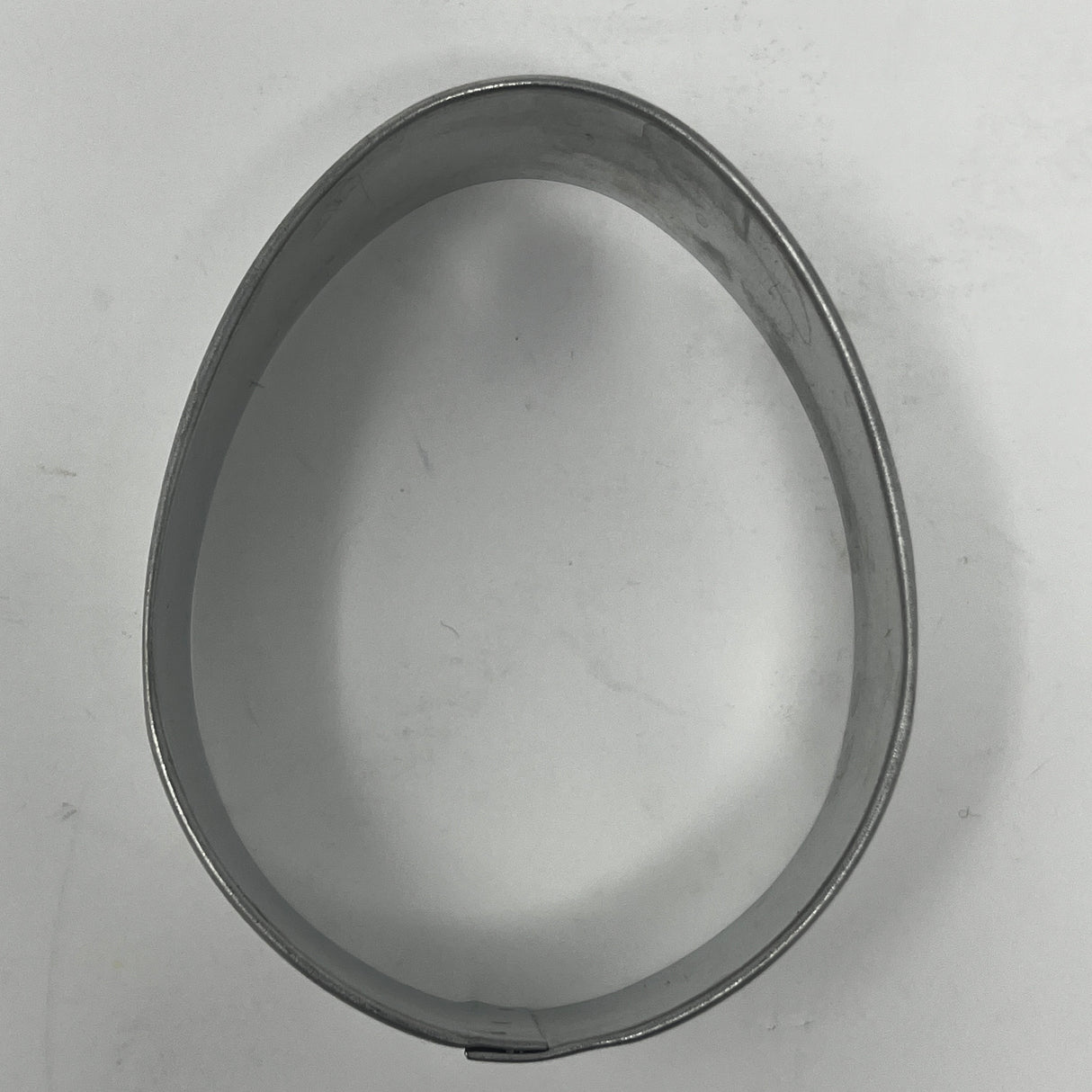 Mid-century metal egg-shaped cookie cutter, part of a collection featuring adaptive handles for easy grip, ideal for creating unique holiday and celestial-themed cookies.