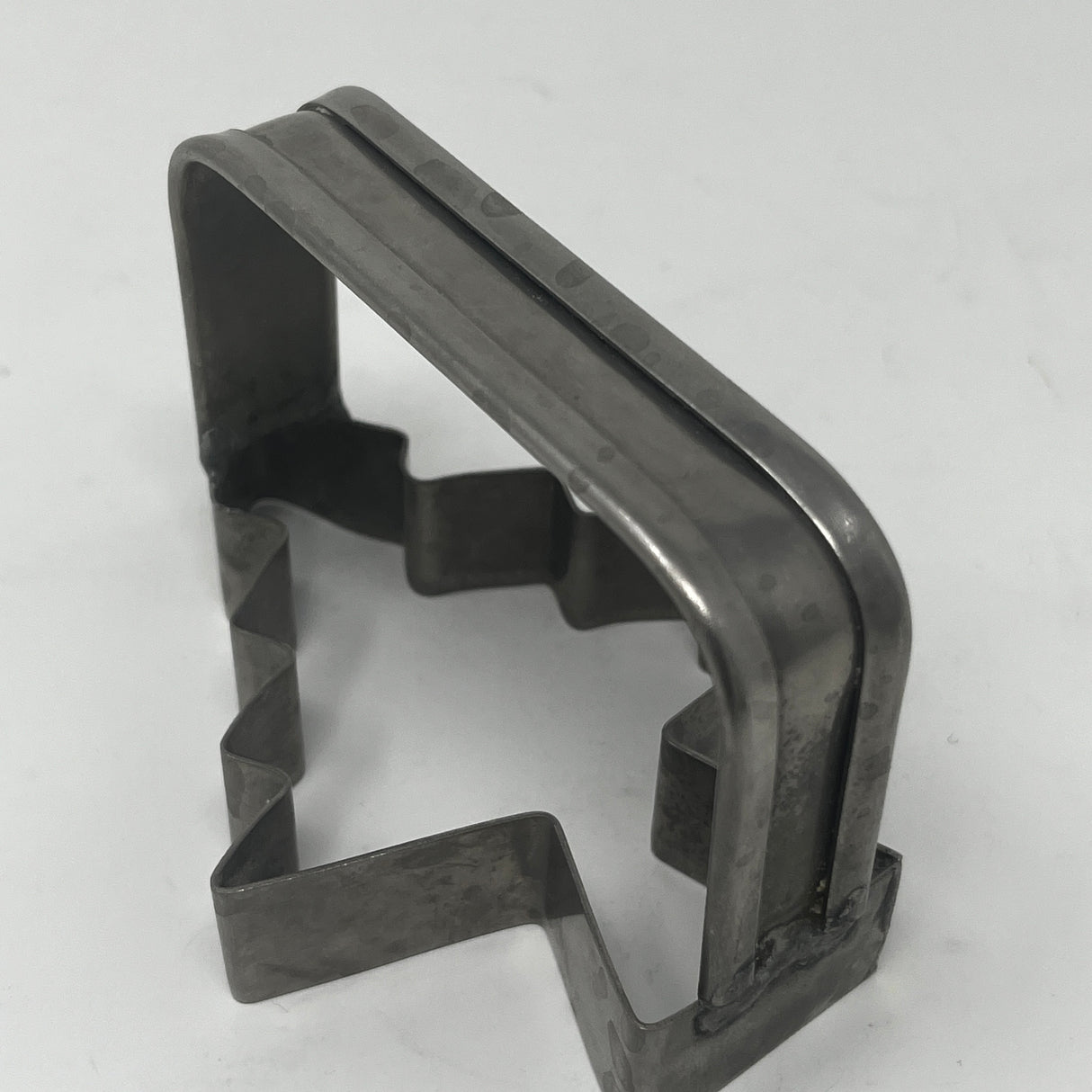 Mid-century metal cookie cutter shaped like a tree, featuring an adaptive design with a large handle for easy grip, part of a collection including vintage items.