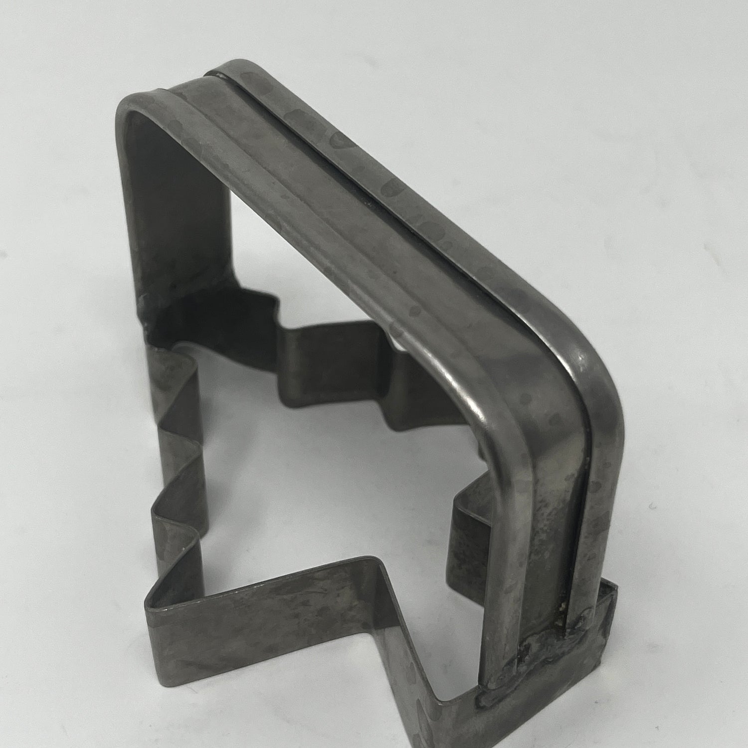 Mid-century metal cookie cutter shaped like a tree, featuring an adaptive design with a large handle for easy grip, part of a collection including vintage items.