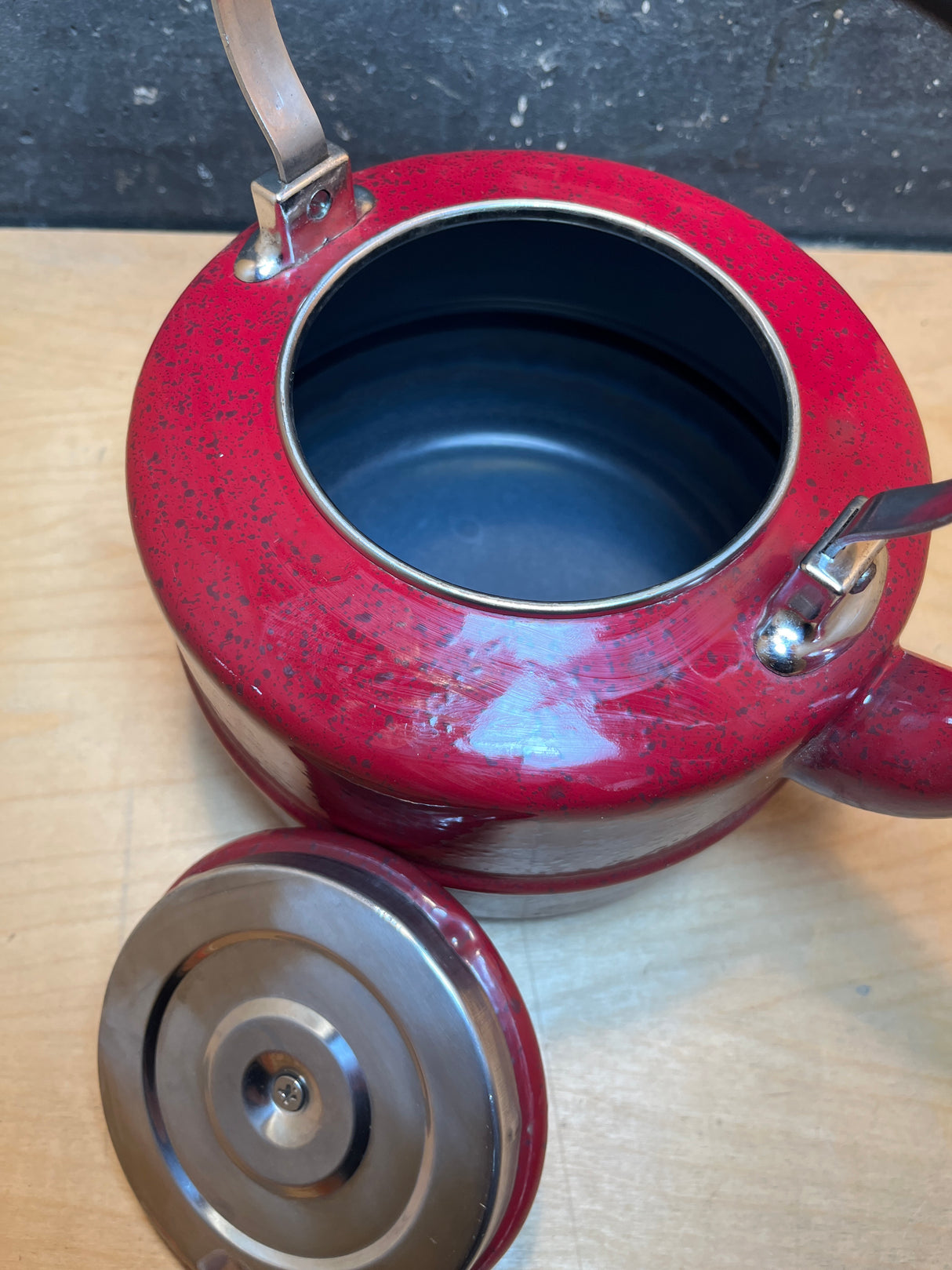 Tea kettle - steel red speckled enamelware - Paula Deen with lid beside, curved spout, and metal handles on light wood surface. Interior is dark-coated.