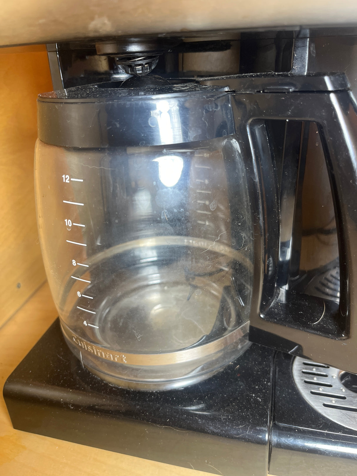 12-cup Cuisinart coffee maker with hot water dispenser, featuring an empty glass carafe on its warming plate, highlighting drip-free spout and customizable brew options.