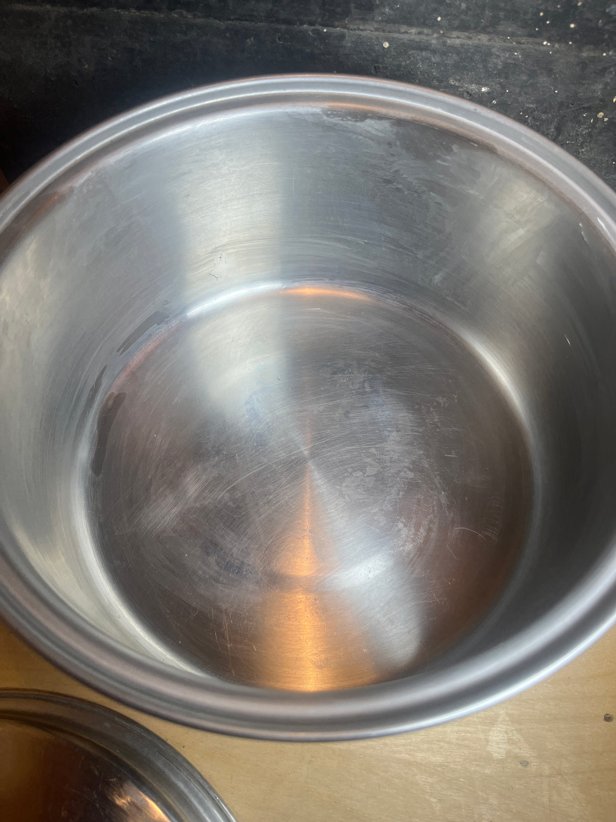 Vintage Duncan Hines 3-ply 18-8 stainless steel stock pot, empty, with lid and black handles, on a wooden surface, highlighting durable construction and ease of use.