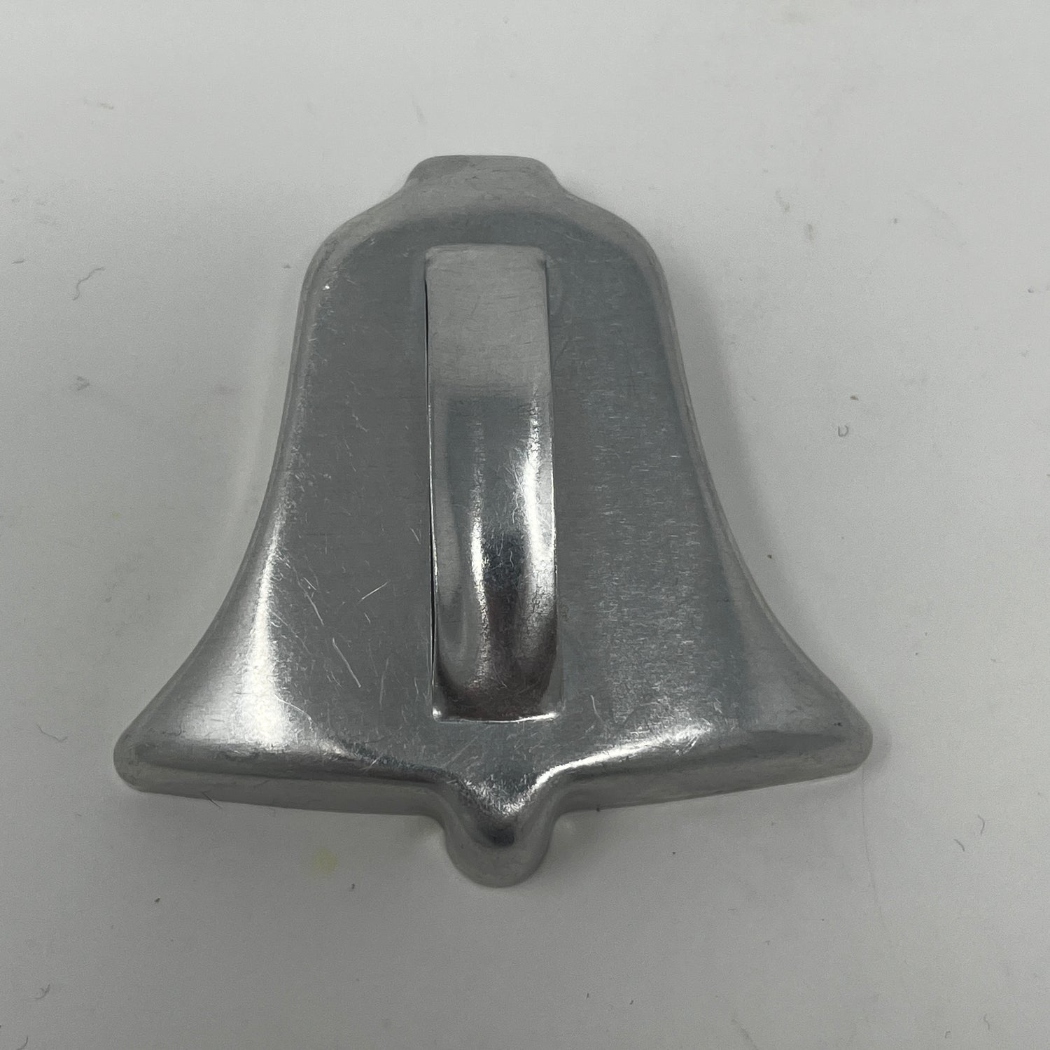 Mid-century metal cookie cutter featuring a silver bell shape with a sturdy metal handle, ideal for easy gripping.
