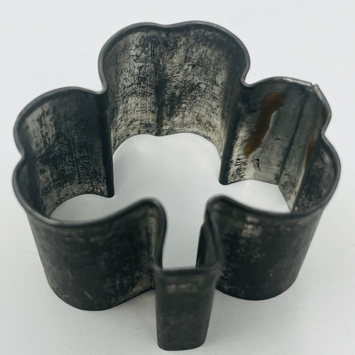 Mid century metal cookie cutter shaped like a clover, featuring an adaptive design with a large handle for easy gripping, ideal for baking enthusiasts.