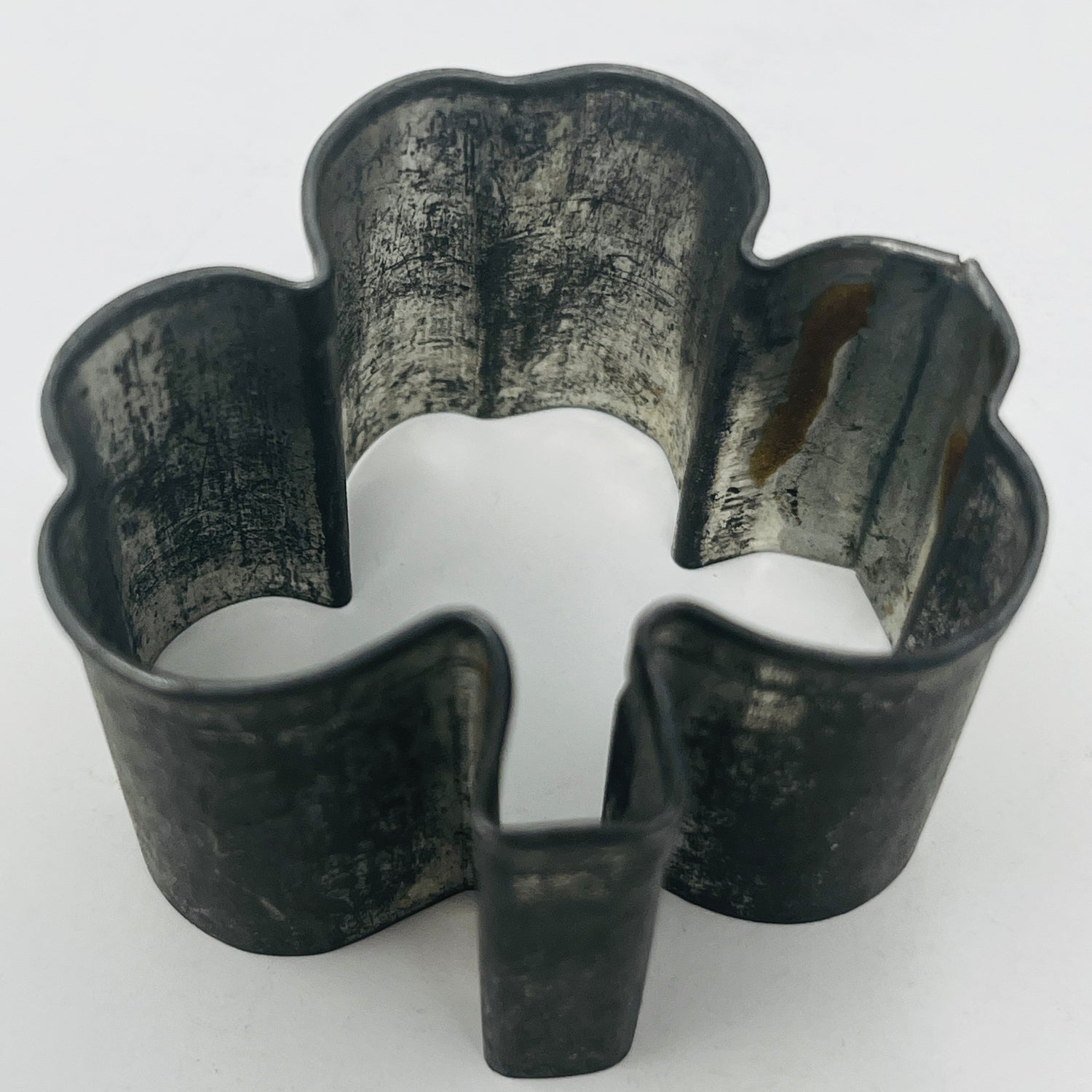 Mid century metal cookie cutter shaped like a clover, featuring an adaptive design with a large handle for easy gripping, ideal for baking enthusiasts.