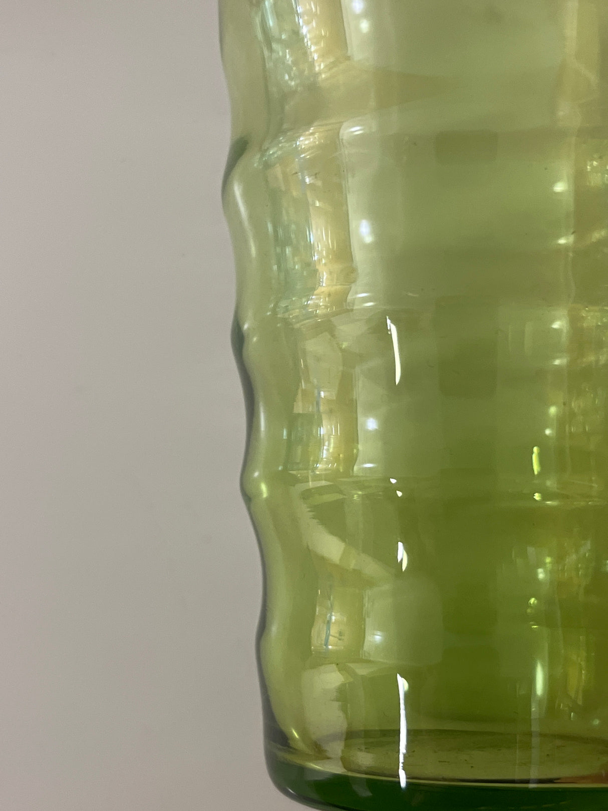 Set of 6 1970s wavy green glass tumblers, showcasing a translucent texture with subtly ridged sides and a rounded bottom edge against a plain backdrop.