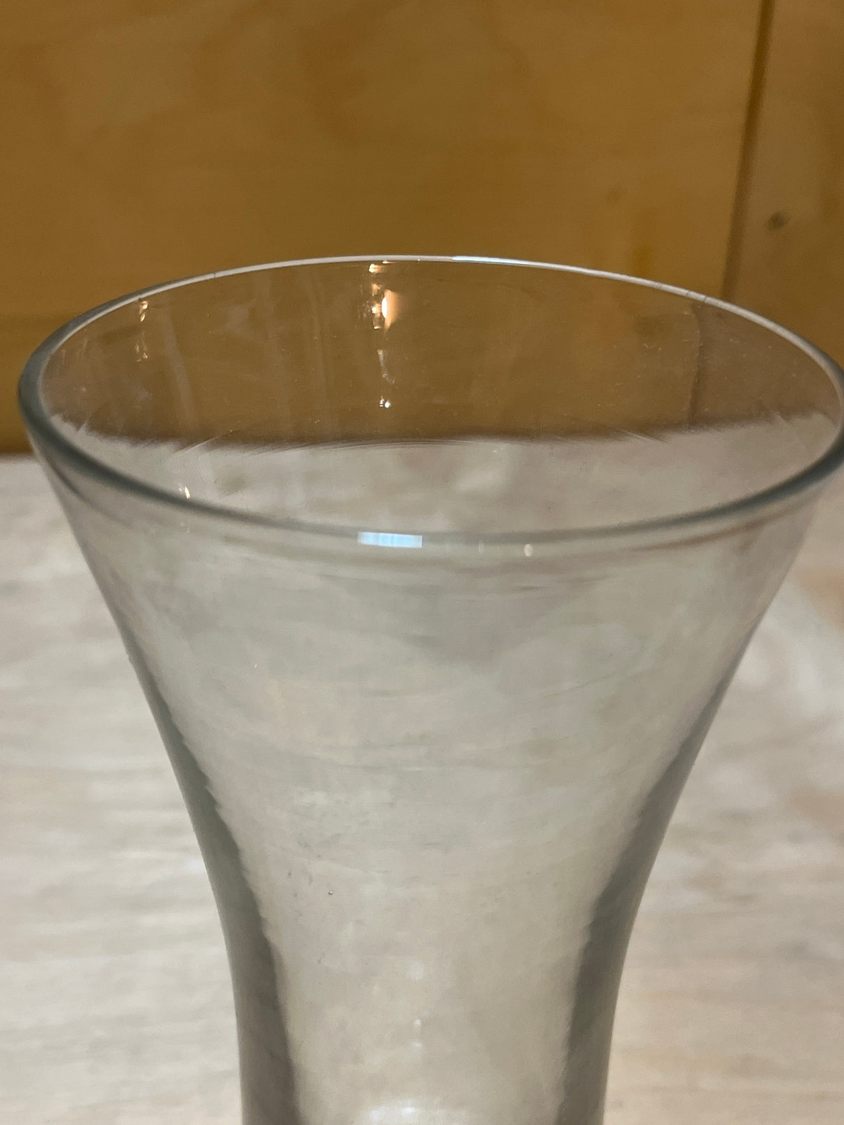 Tall Pilsner beer glass with gently flared sides, a wider opening at the top, and a sturdy weighted base, sitting on a light surface.