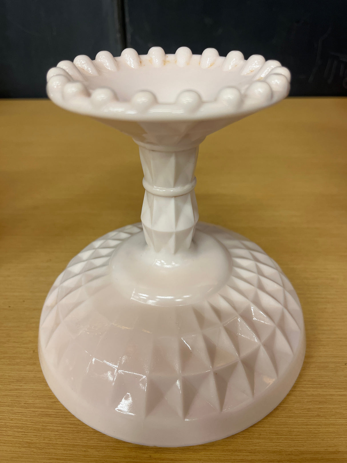 Jeanette pale pink milk glass pedestal candy dish showcasing a geometric crisscross base and raised bumps on the rim, highlighting its vintage elegance.