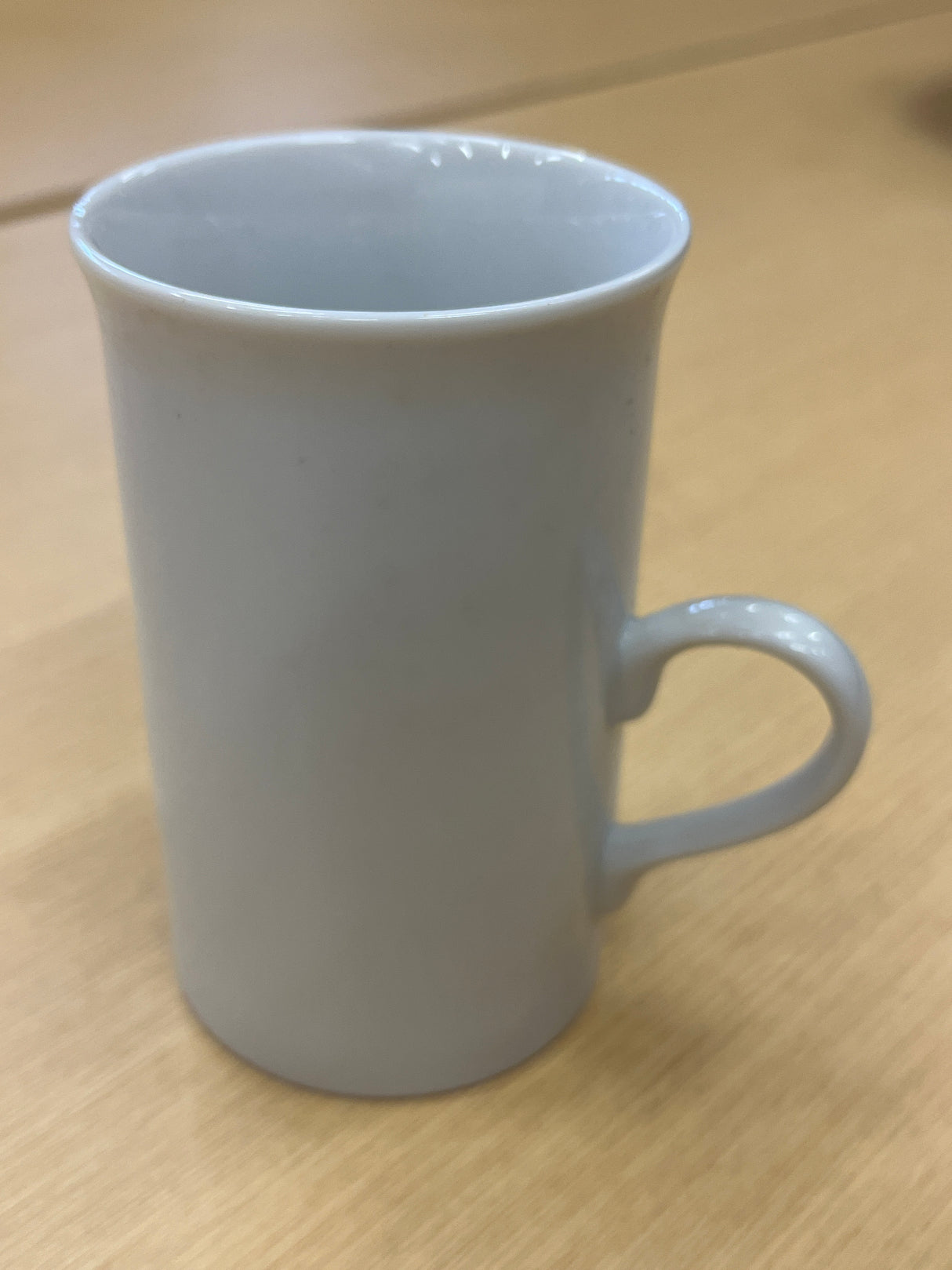 Tall ceramic white coffee mug with a smooth finish and delicate, modern handle, perfect for everyday use.