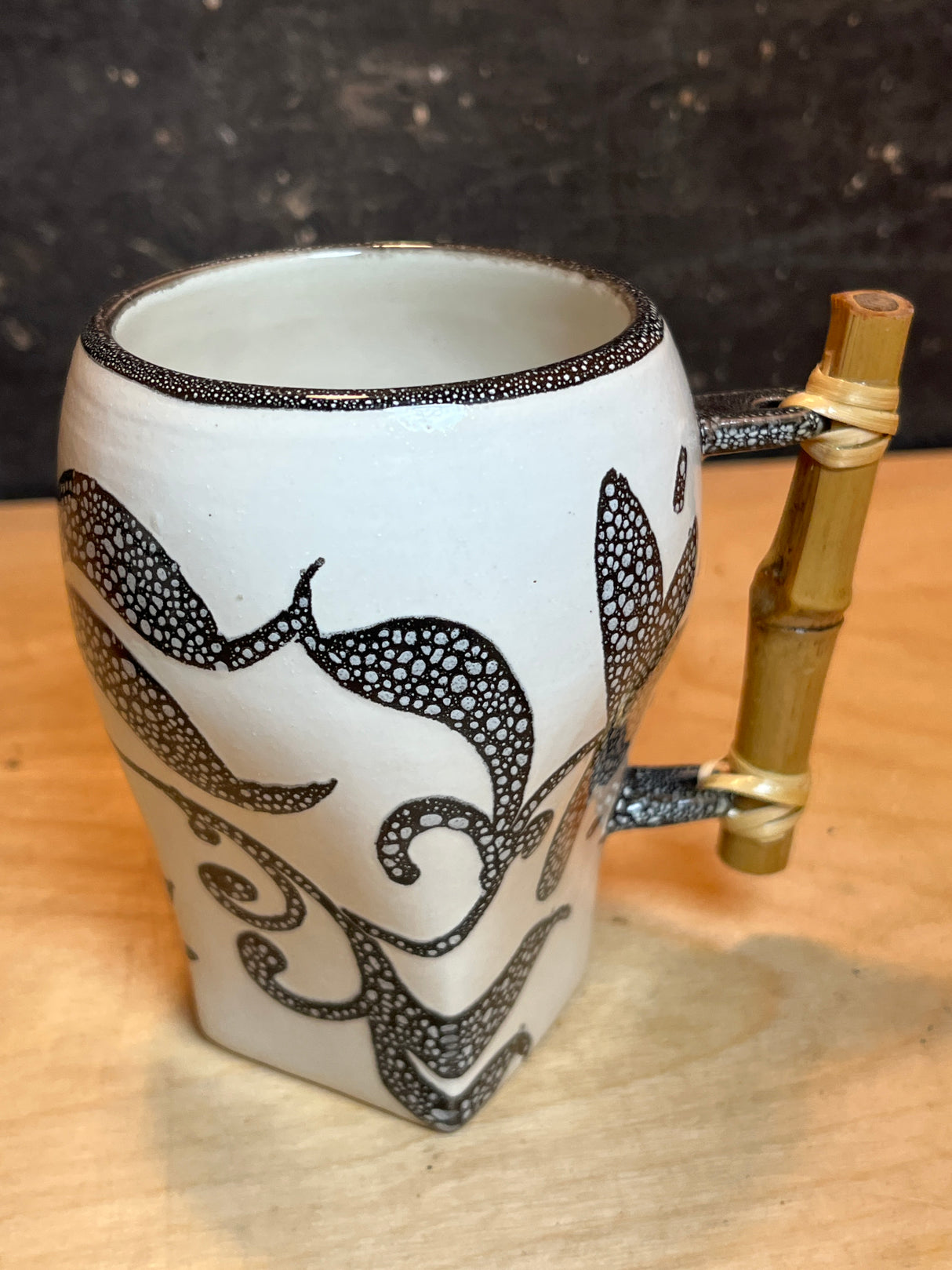 Hand-crafted ceramic mug with a black bubbled-dot pattern and bamboo handle, part of an 8-piece set with a floral-patterned sugar bowl featuring bamboo handles.