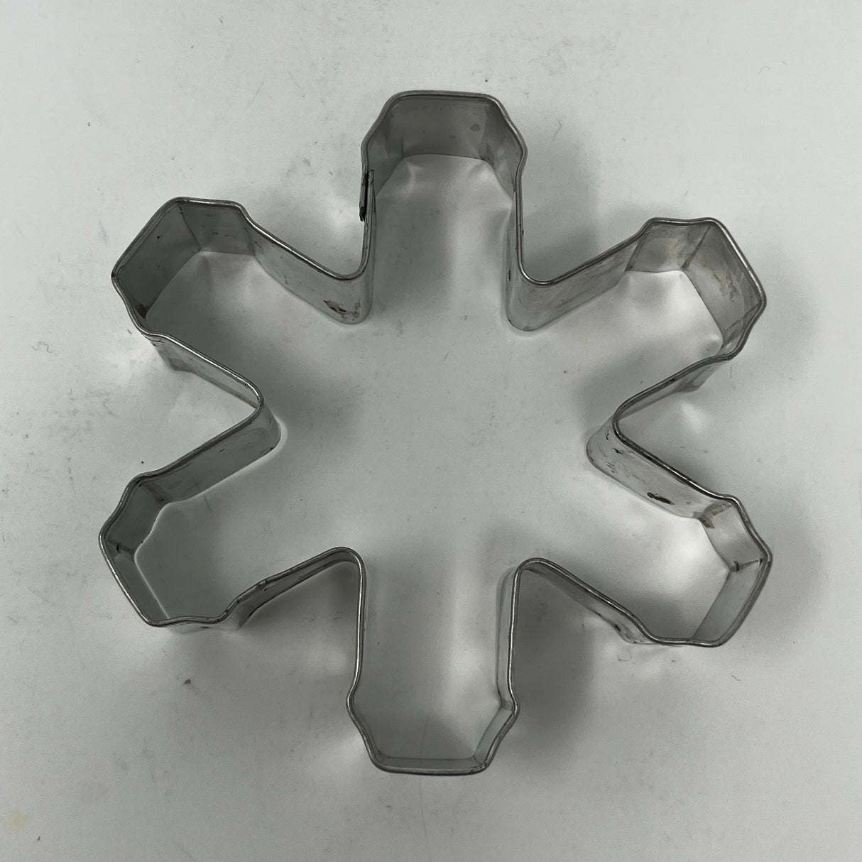 Mid-century metal cookie cutter on white surface, part of an adaptive collection with easy-grip handles, featuring designs from Christmas favorites to 1930s celestial shapes.