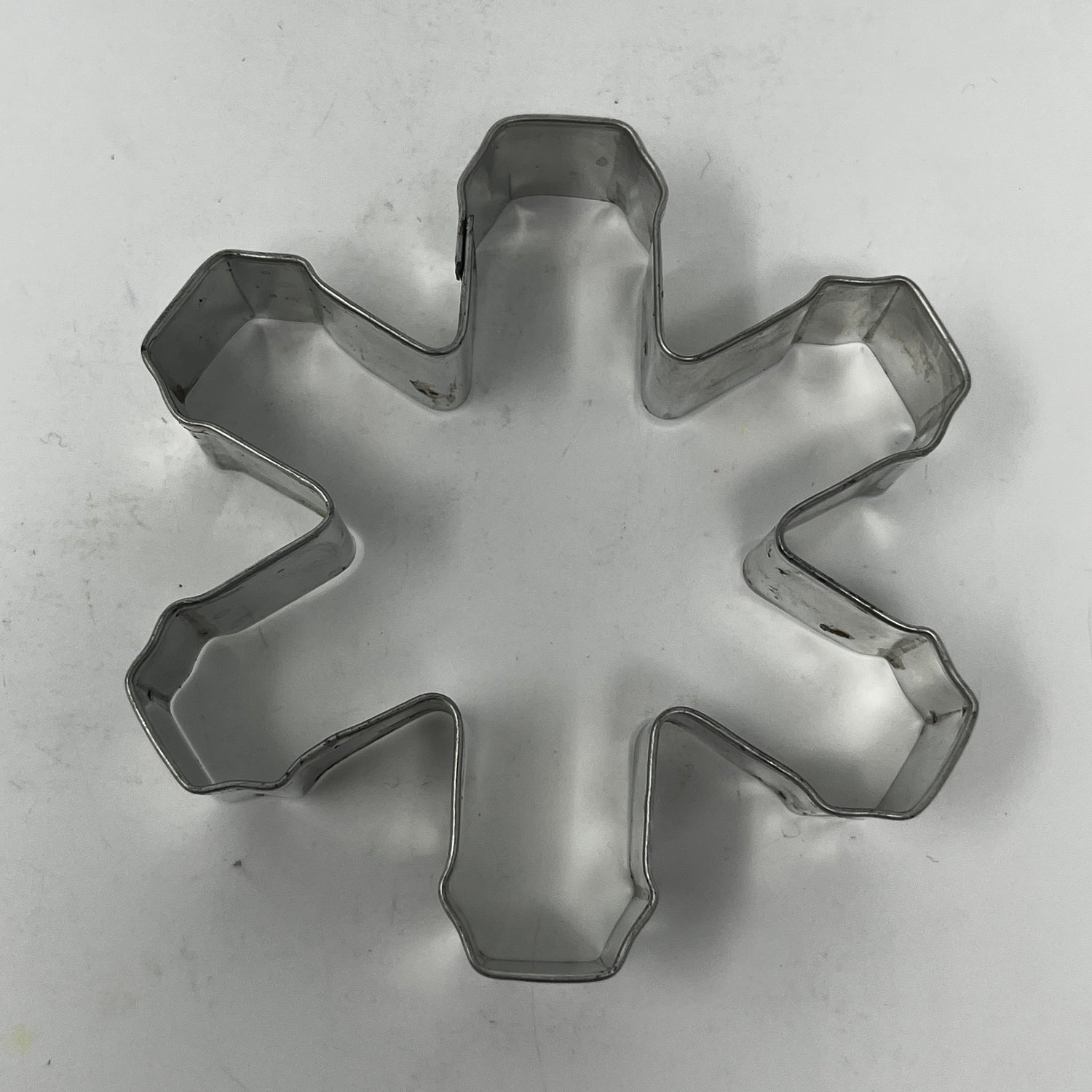 Mid-century metal cookie cutter on white surface, part of an adaptive collection with easy-grip handles, featuring designs from Christmas favorites to 1930s celestial shapes.
