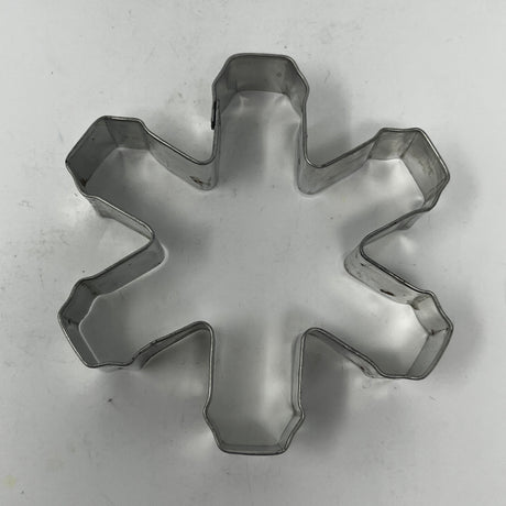 Mid-century metal cookie cutter on white surface, part of an adaptive collection with easy-grip handles, featuring designs from Christmas favorites to 1930s celestial shapes.