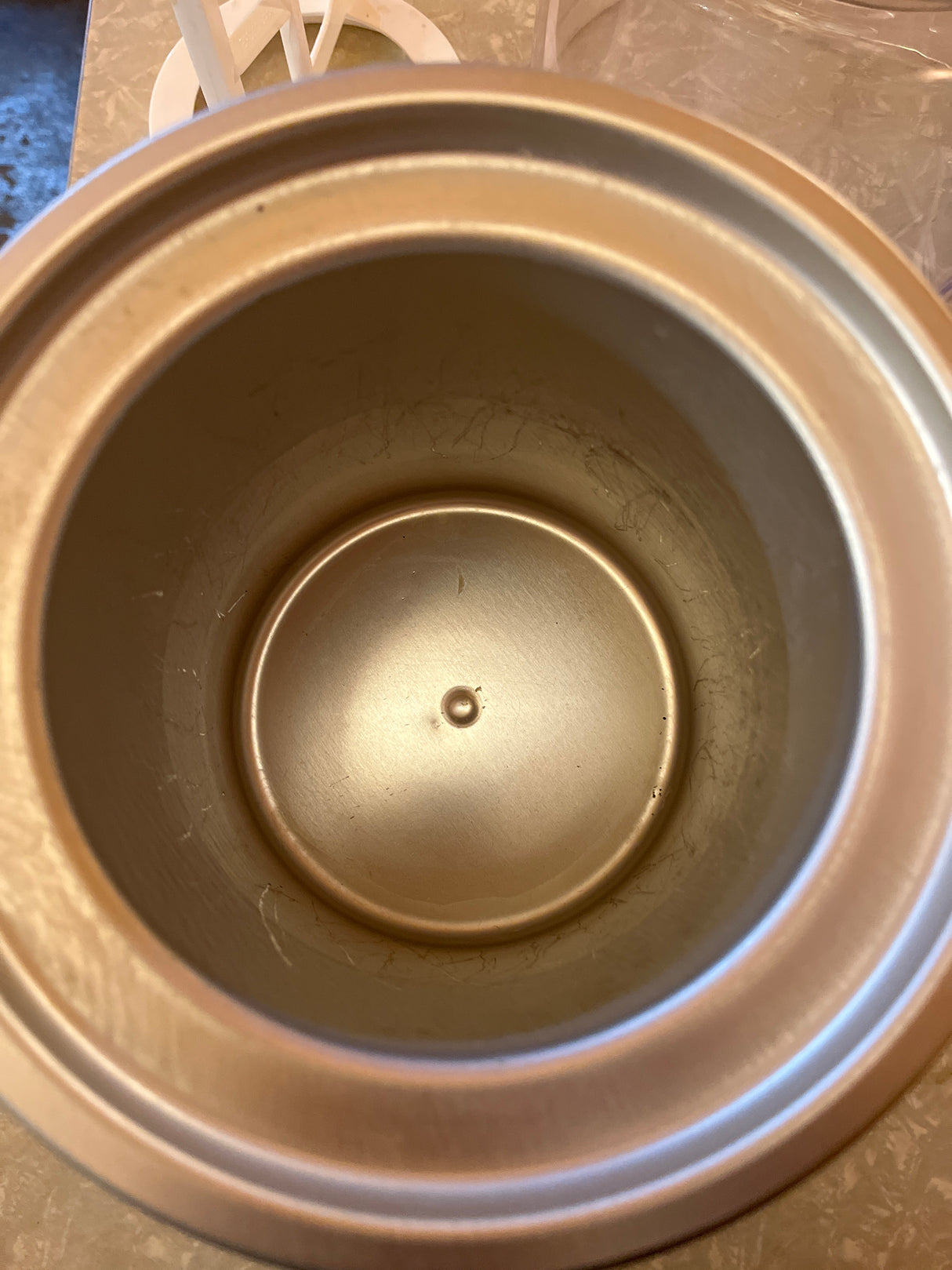 Interior view of the Hamilton Beach 68880 Automatic Ice Cream Maker's gold-colored, double-insulated canister, showcasing its smooth, slightly scratched interior and dimpled bottom.