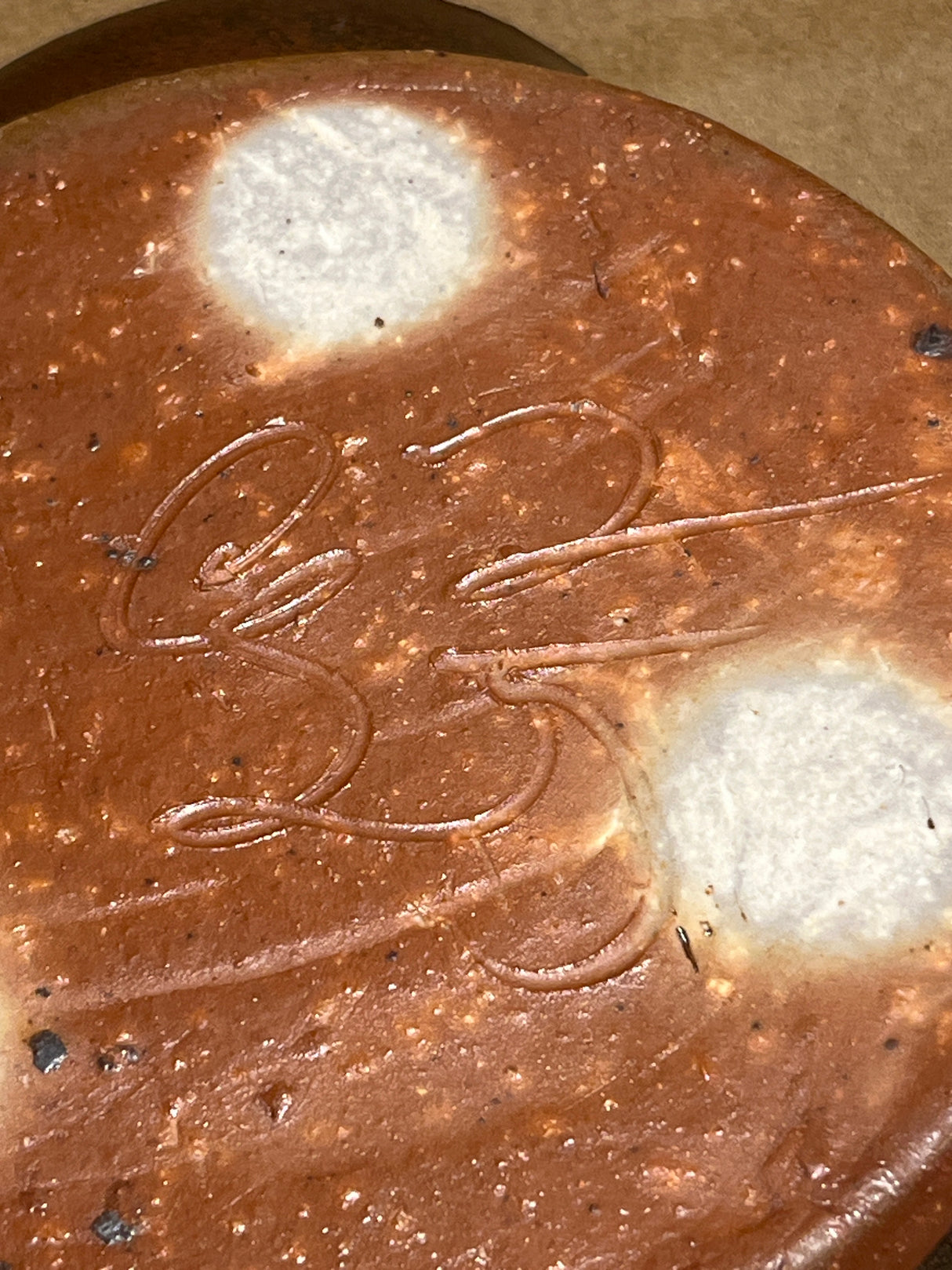 Handmade ceramic garlic grater spoon rest by Charles Lehman, showing the underside with two unglazed stilt marks and the potter's signature.