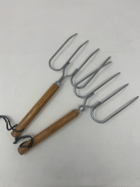 Set of two vintage roast forks with wooden handles, ideal for grilling meats and whole vegetables, showcased among other tools and kitchen utensils.