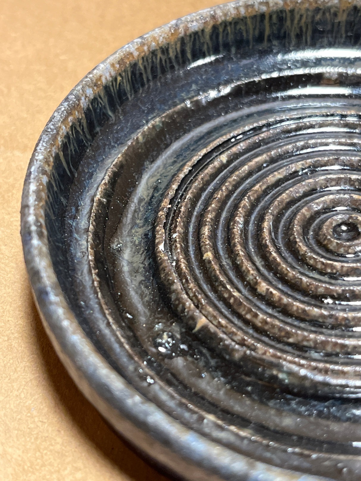 Handmade ceramic garlic grater spoon rest by Charles Lehman, featuring a spiral-grooved base and drip-style glaze, highlighting its handcrafted, functional design.