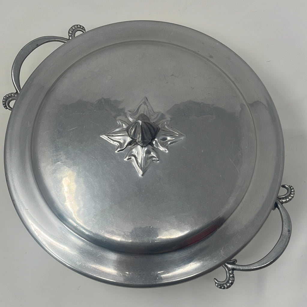 Vintage aluminum casserole carrier with intricate handles and lid knob, perfect for elegantly presenting baked dishes.